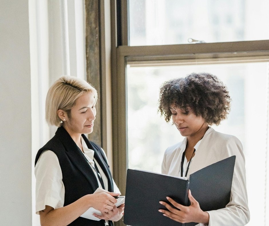 African American woman showing a white woman something in a notebook