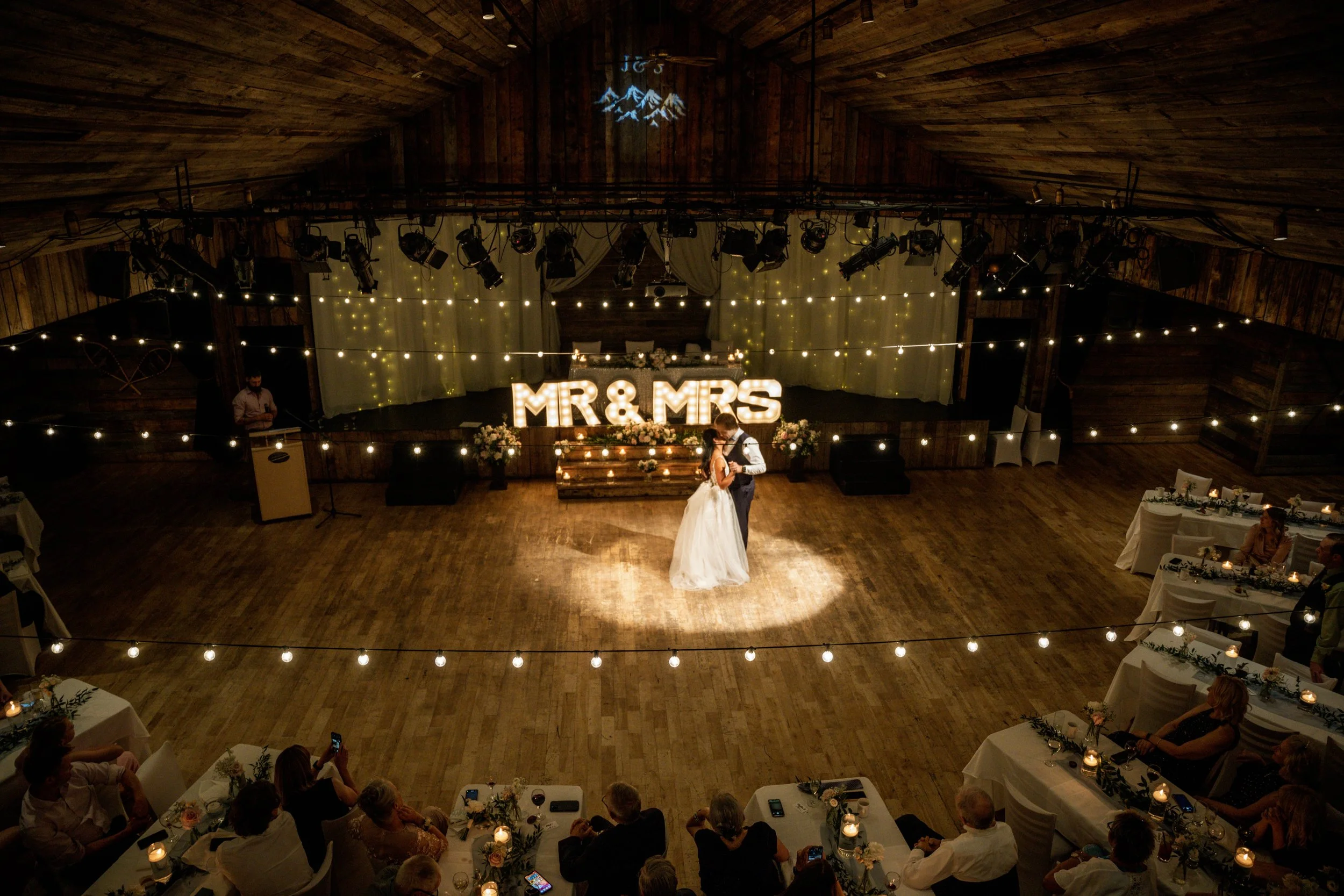 A bride and groom dance together in a decorated wedding venue with 