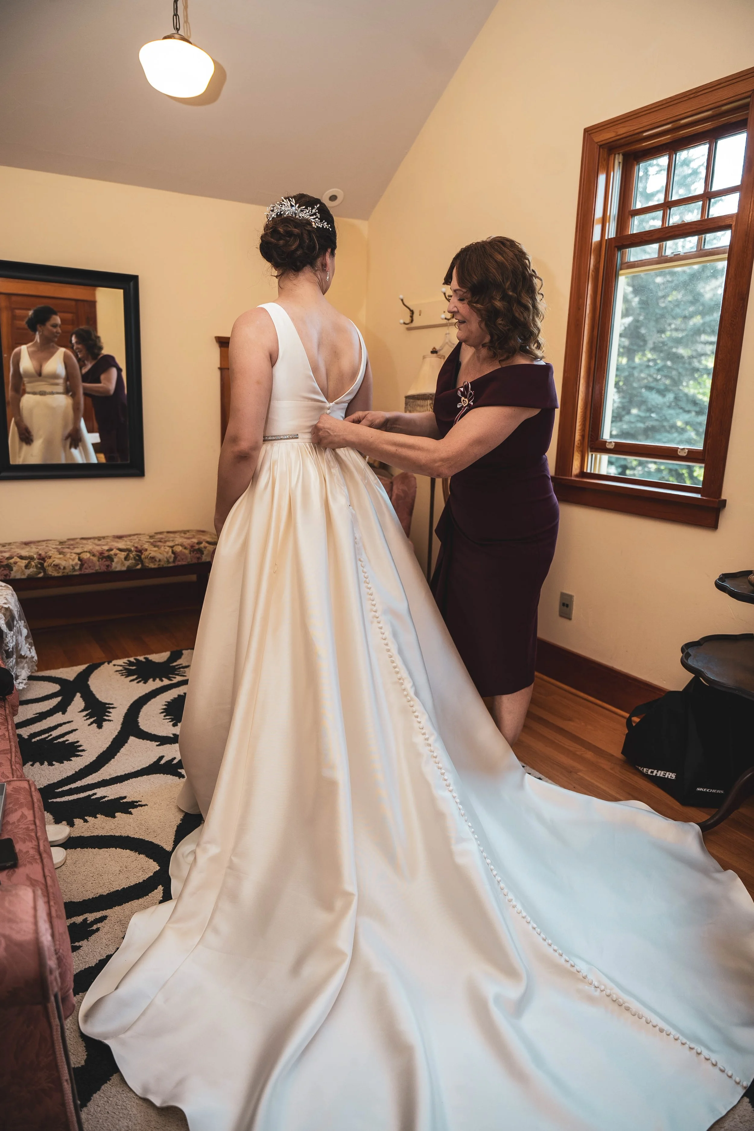 Mother helping bride Michaela button her wedding dress during getting ready Calgary