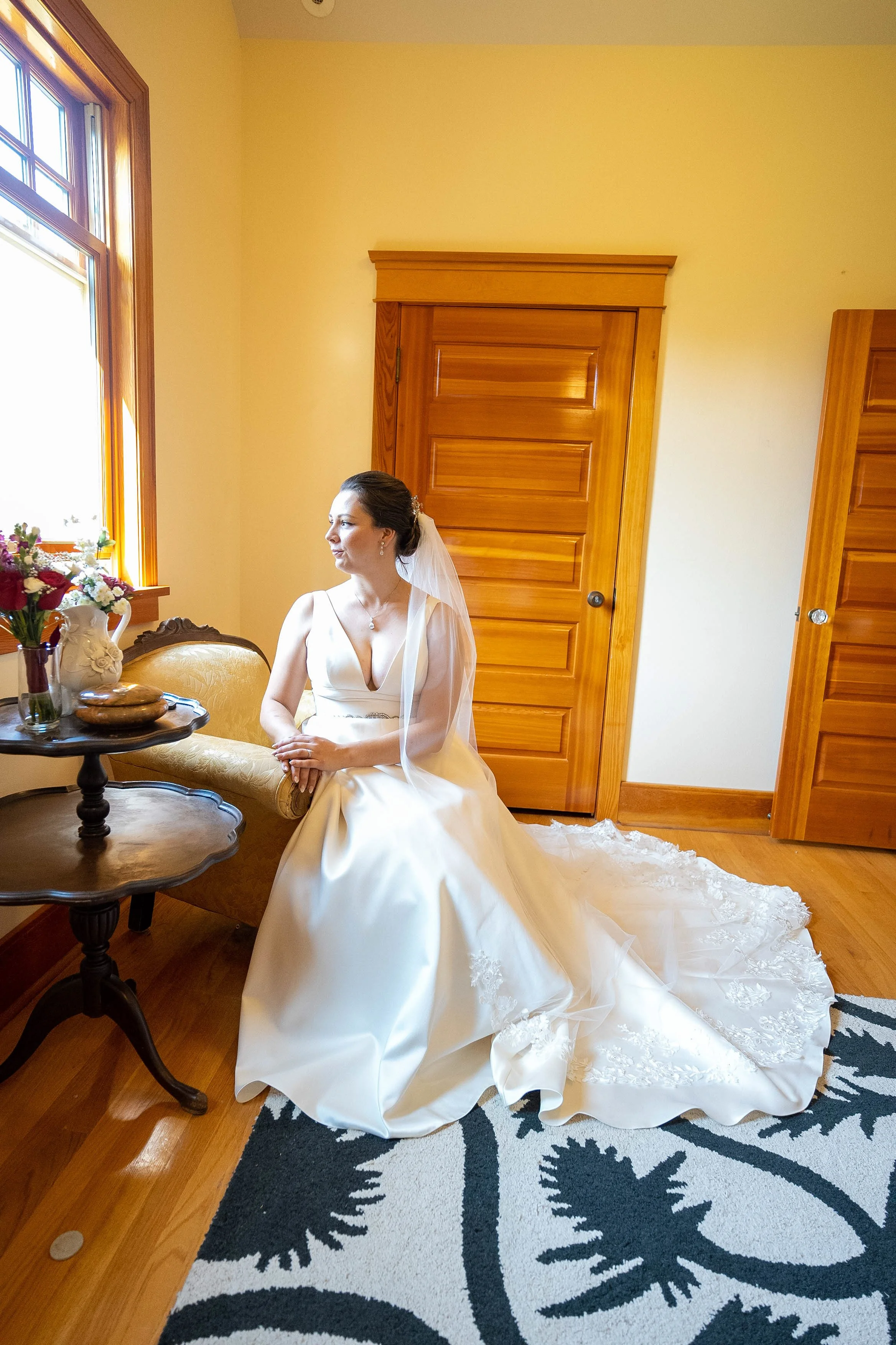 Bride Michaela in full wedding dress and veil seated by the window during getting ready Calgary
