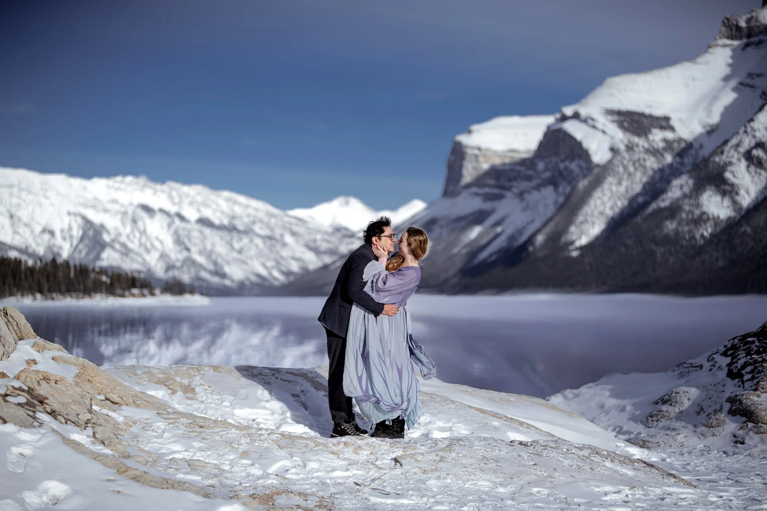 Winter couple portrait beside Lake Minnewanka in Banff