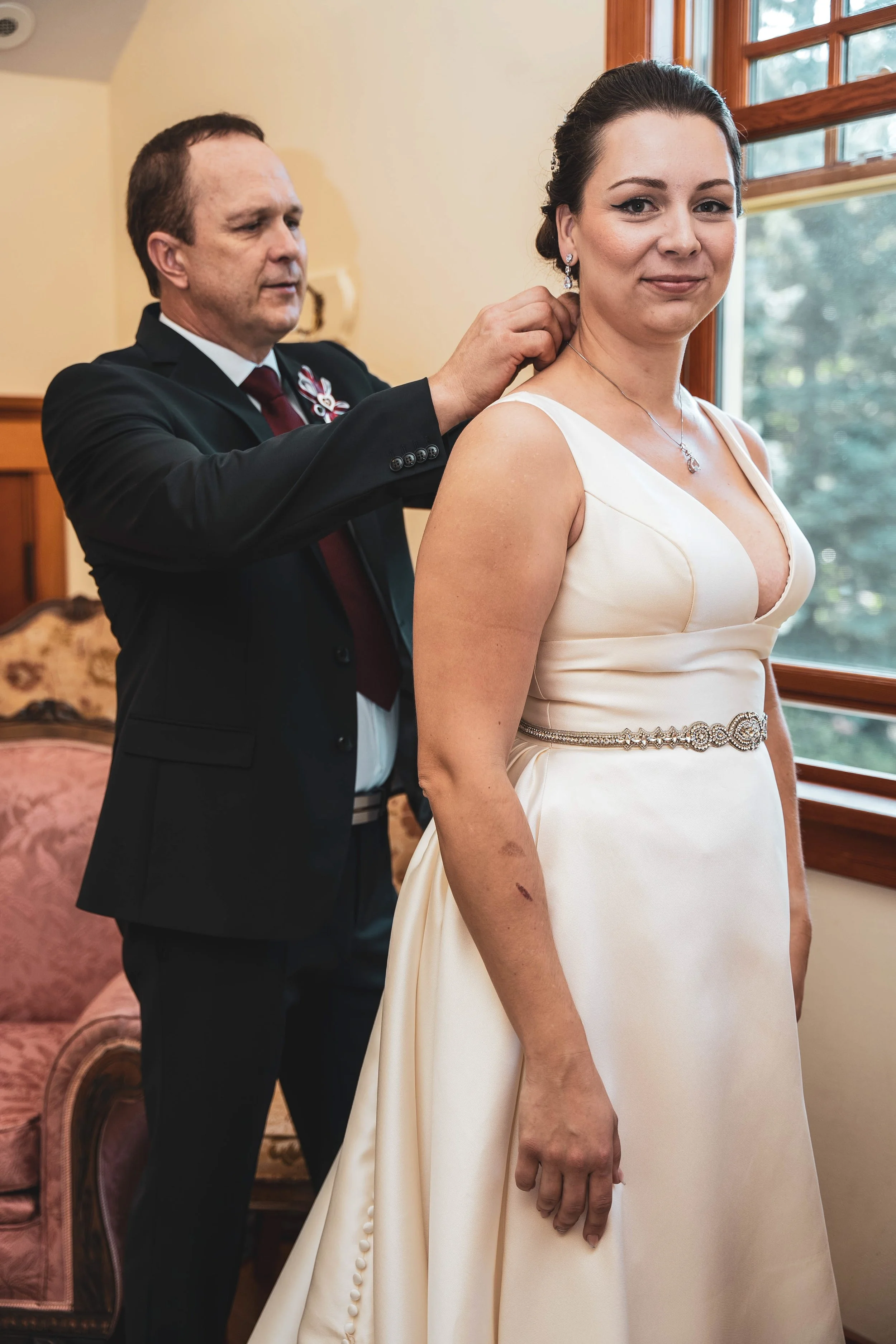 Father clasping bride Michaela's necklace during wedding morning getting ready Calgary