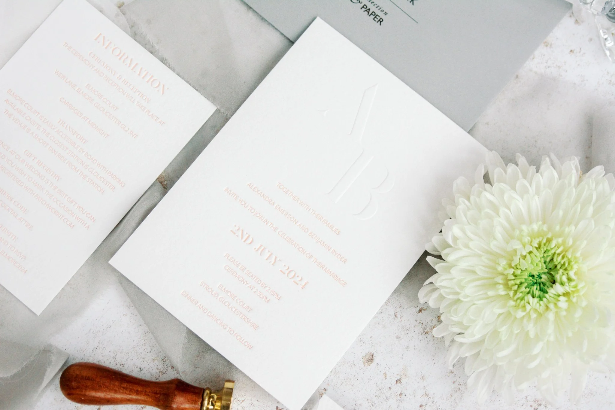 Wedding invitation suite with plant and flower on a white surface.