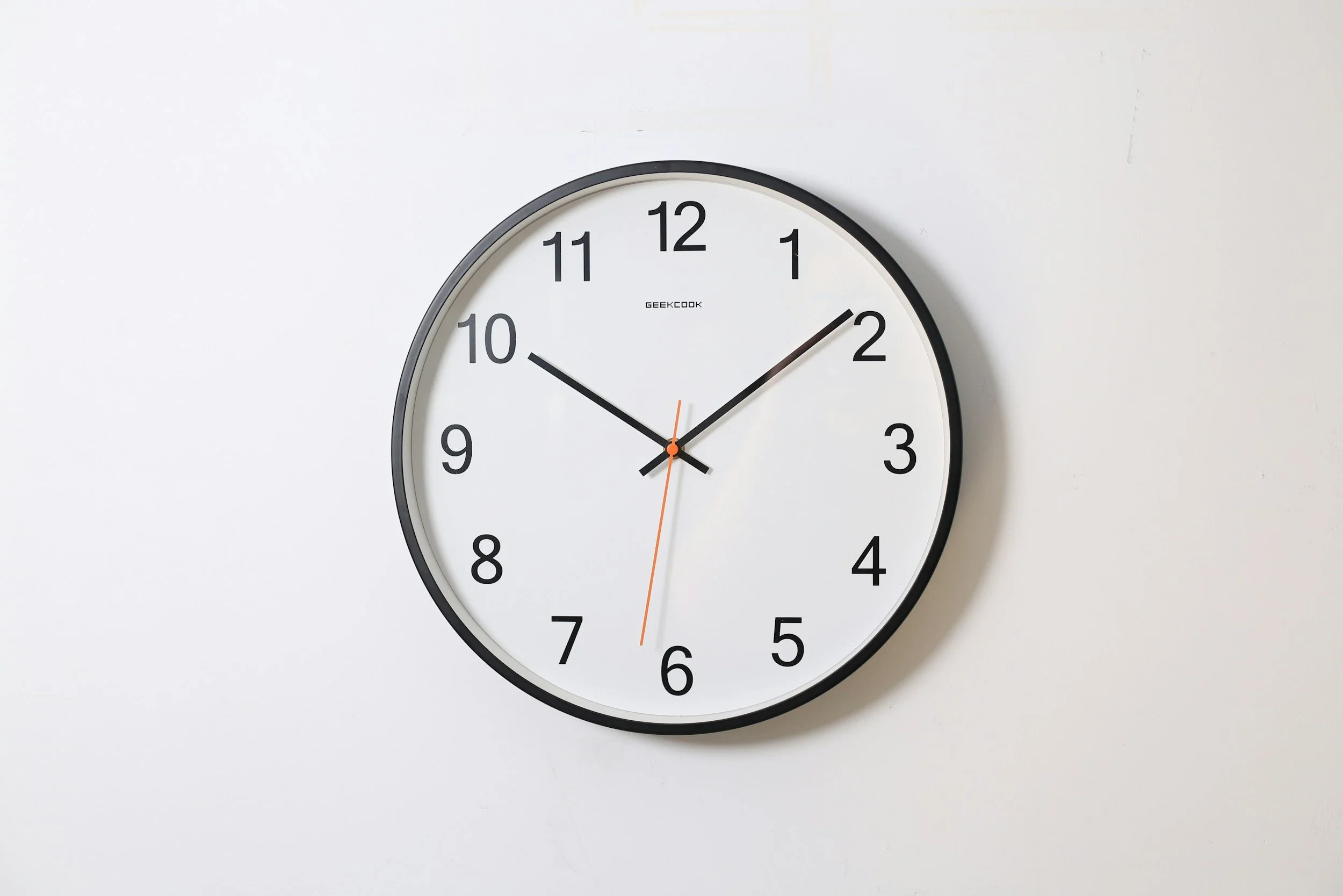 A round wall clock showing the time as 10:09:29 on a white wall.