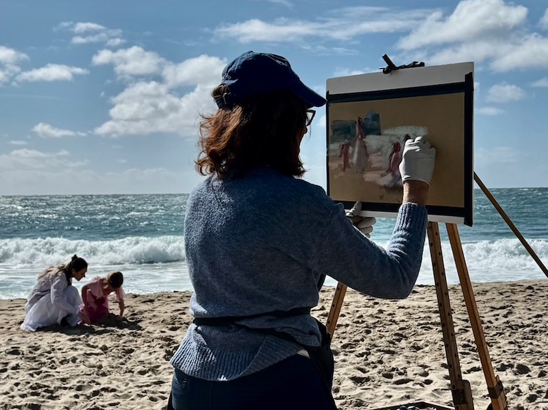 Photo of Mary Aslin painting at the beach