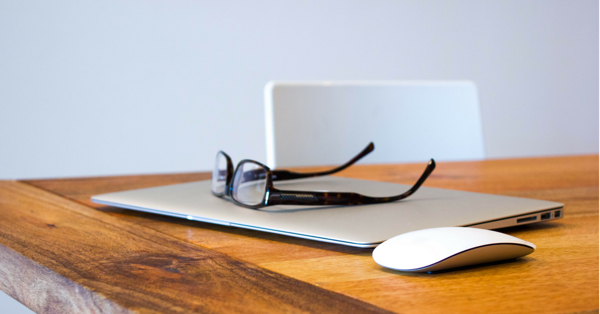 closed laptop, mouse and glasses sitting on laptop. Serene and calm photo, clean wooden table