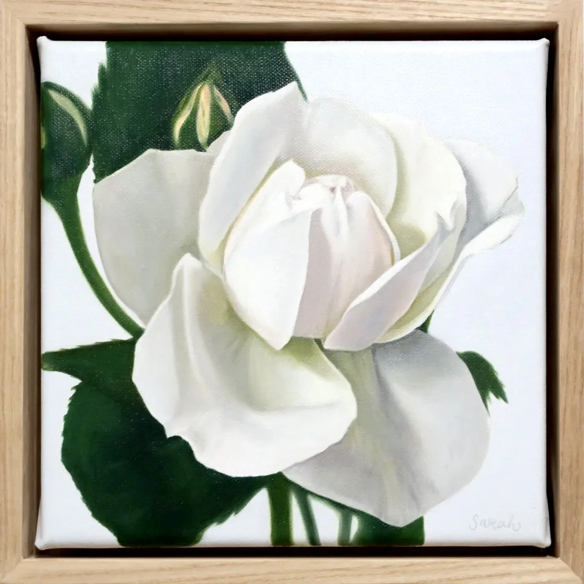 A painting of a white rose with green leaves in a wooden frame.