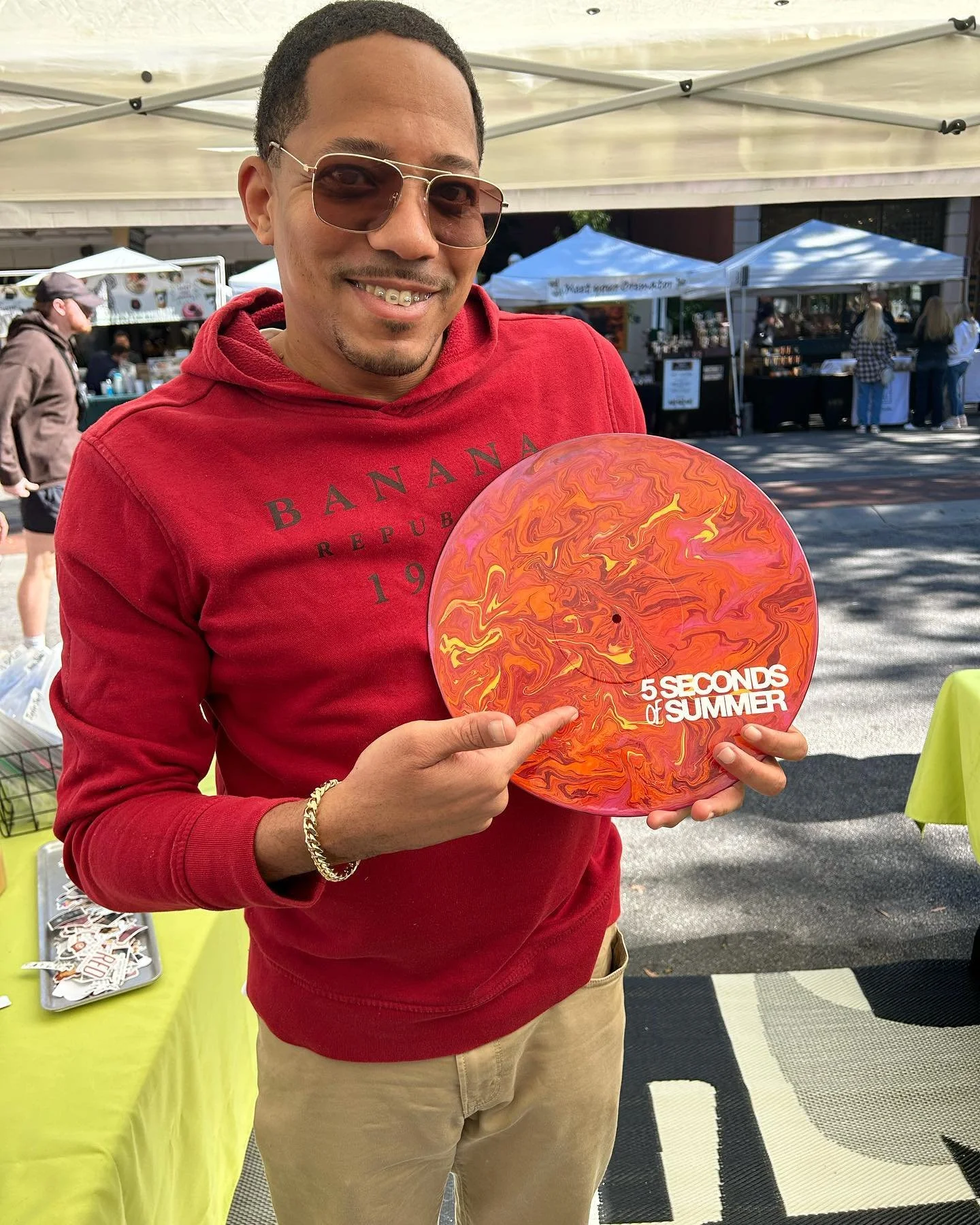 A painted vinyl record on a turntable with a colorful, swirled design and the words "All You Need Is Love" in white and red text.
