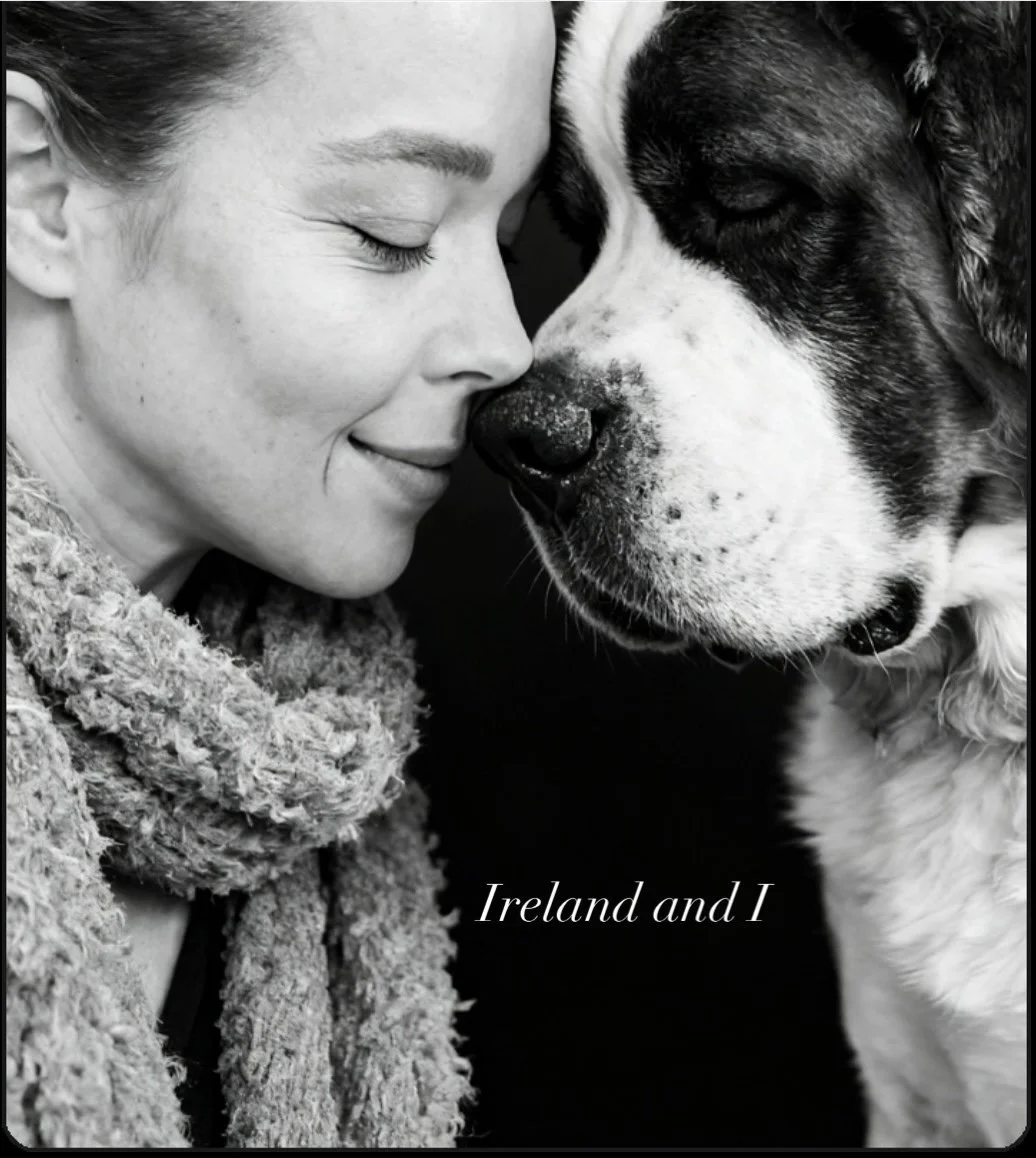 Black and white photo of a woman and a dog touching noses with their eyes closed, woman wearing a textured scarf, with text 'Ireland and I' at the bottom.