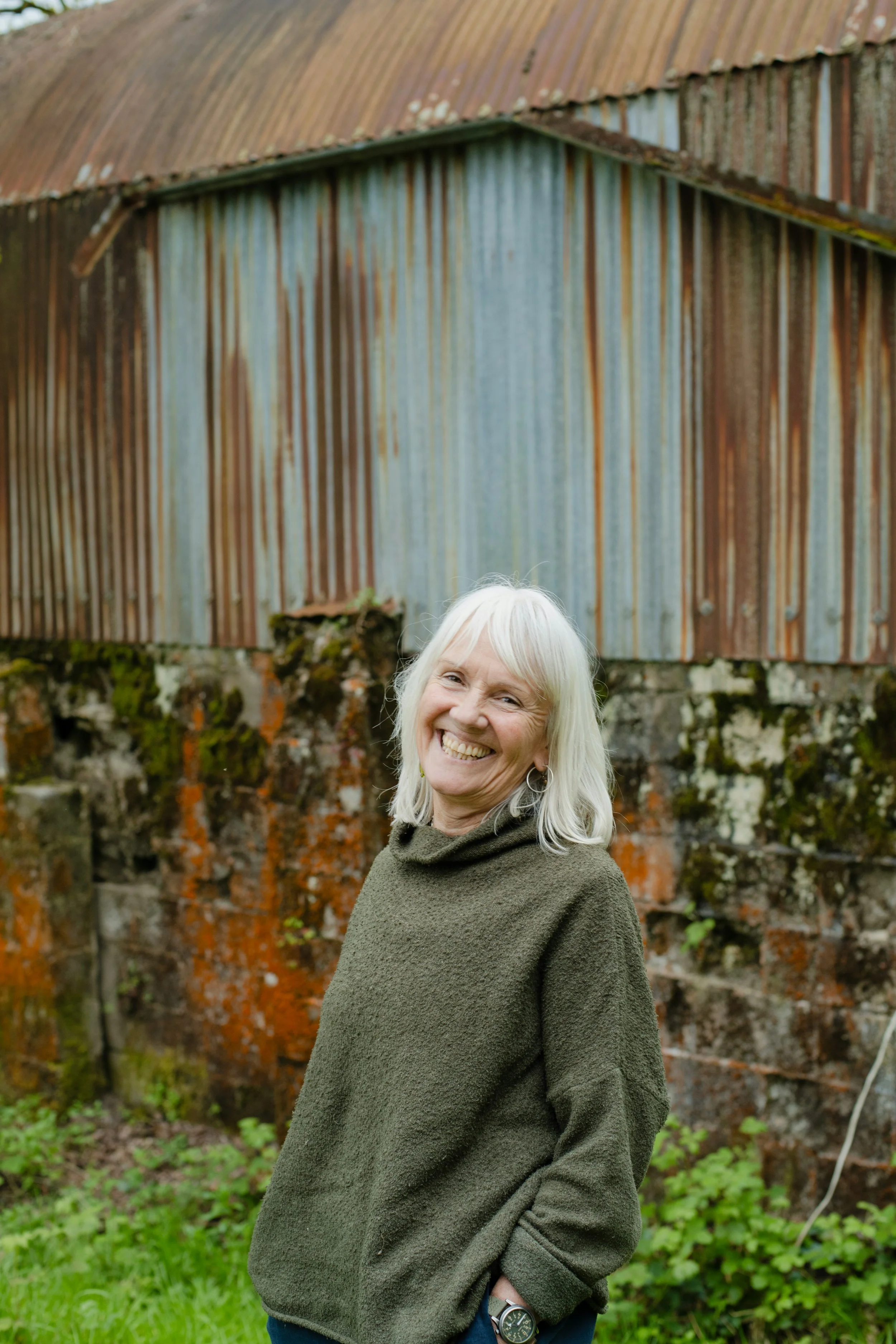 Older woman with a joyful expression standing in front of a rusty fence