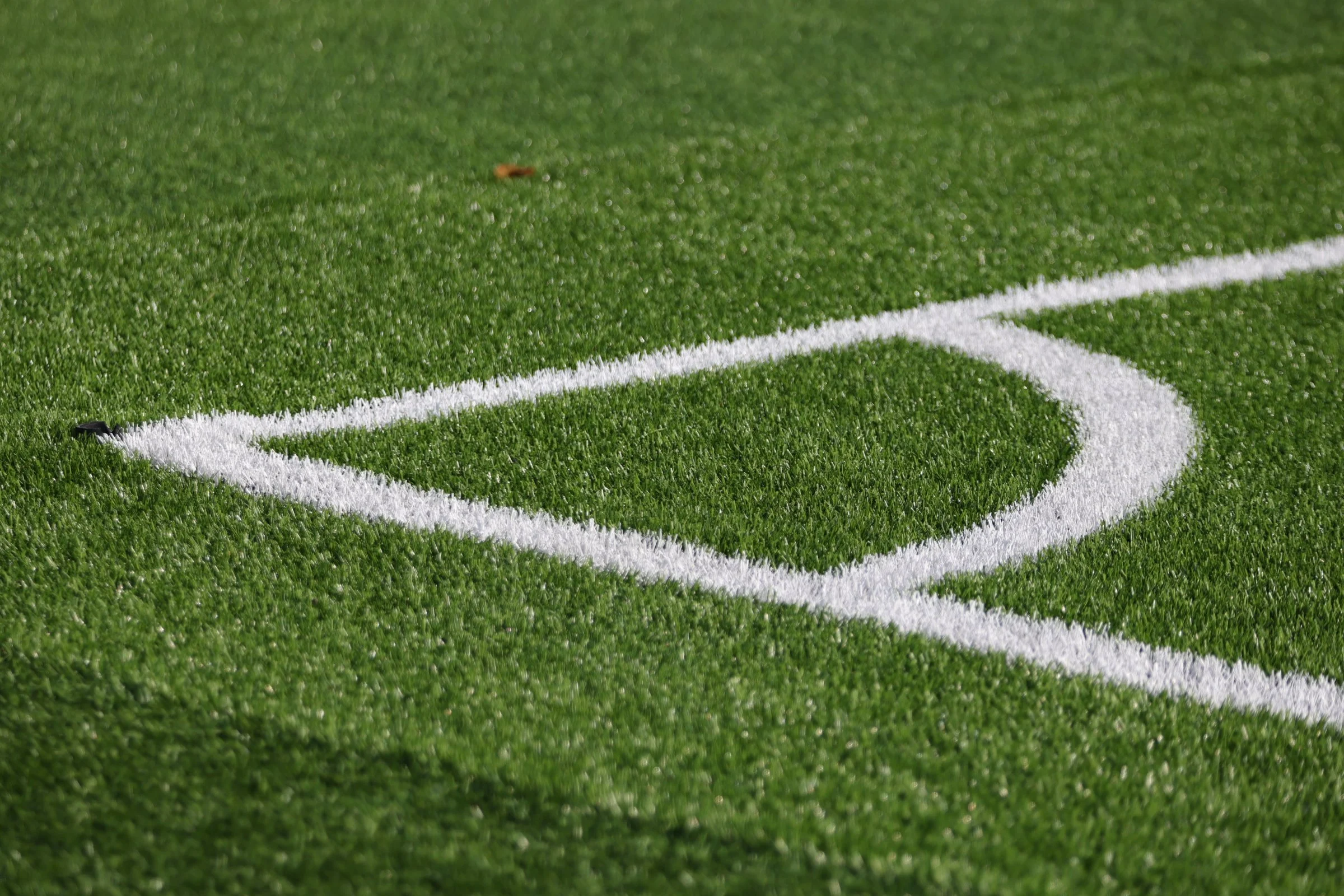Close-up of a football field's synthetic grass showing the white yard line marking.