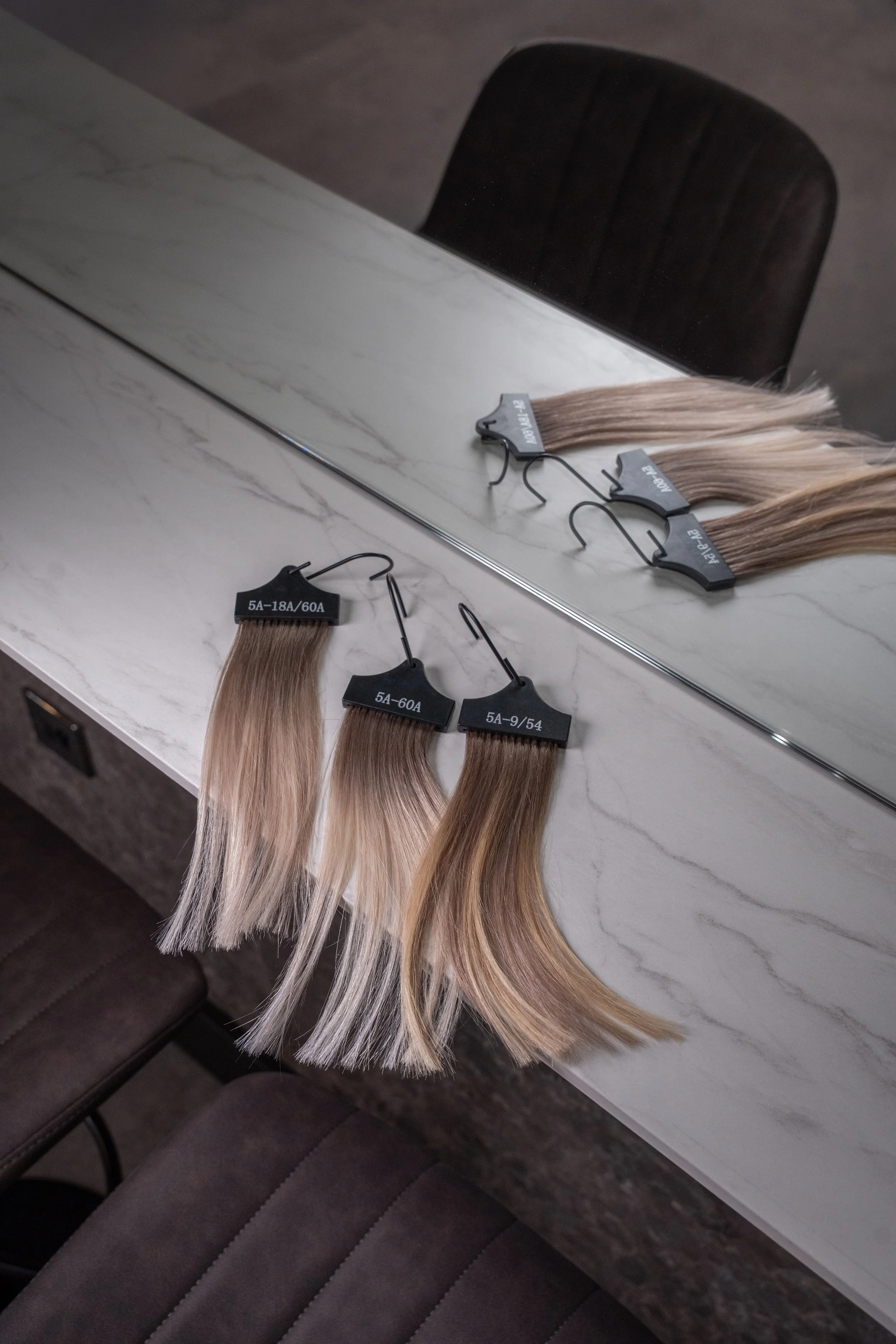 Brand photography for Sloane Salon showing hair extension swatches, styled for salon marketing and content.