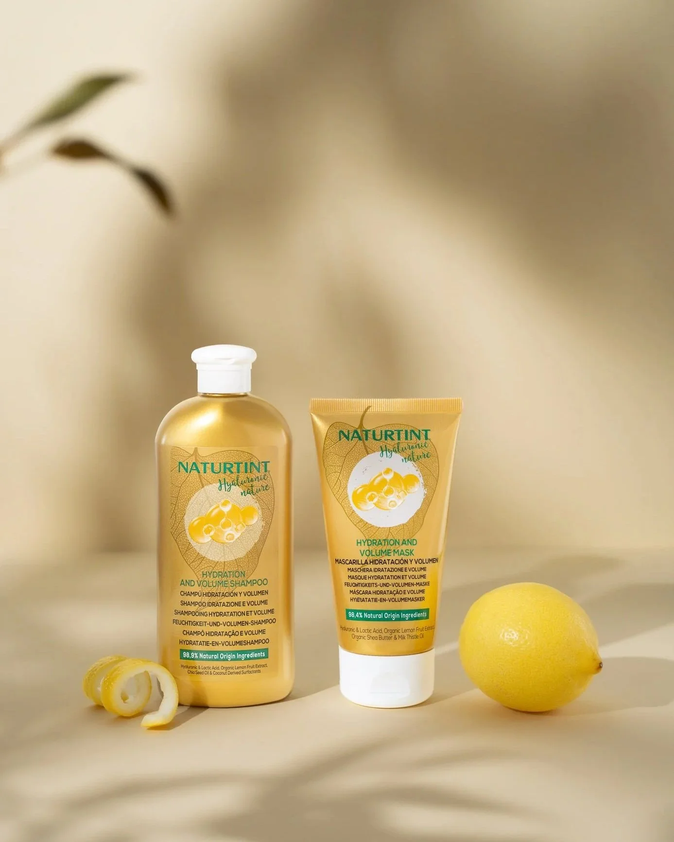 Naturtint shampoo and hair mask styled with fresh lemon in a warm studio product photography setup