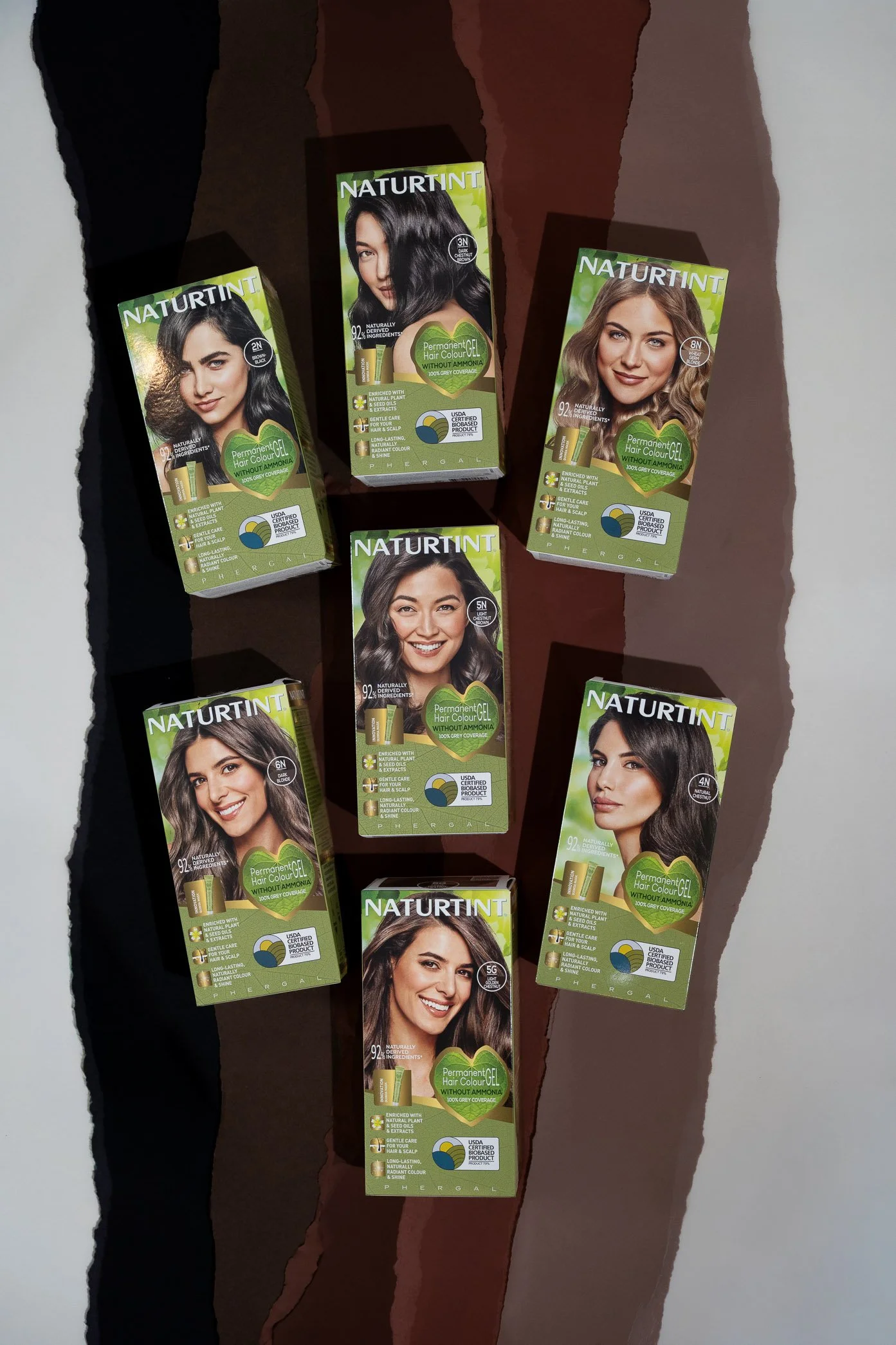 Naturtint permanent hair colour packaging arranged across layered torn paper backgrounds