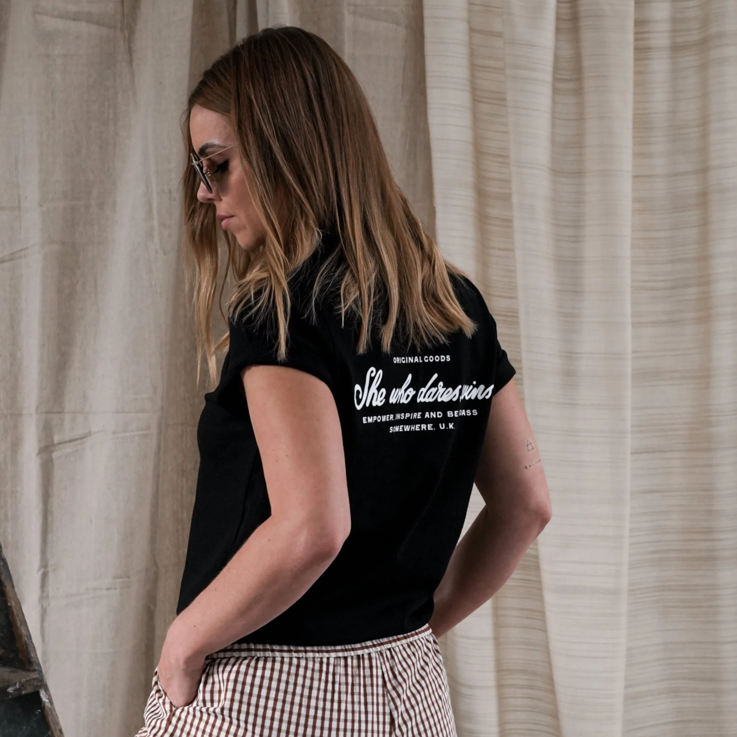 Model wearing She Who Dares Wins clothing during a lifestyle brand photography shoot.