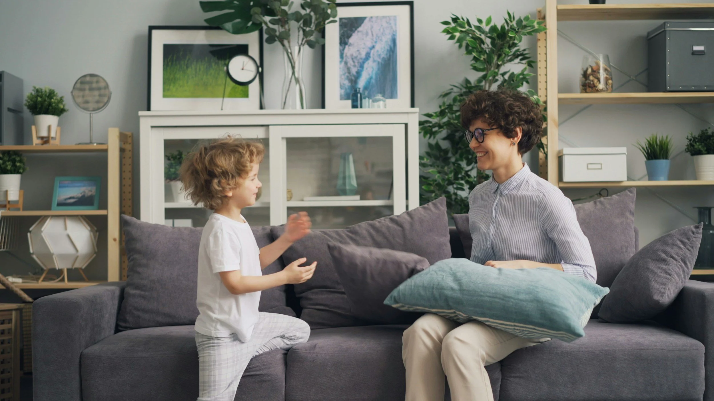 A woman and a young boy sitting on a couch in a living room, engaging in conversation and smiling.