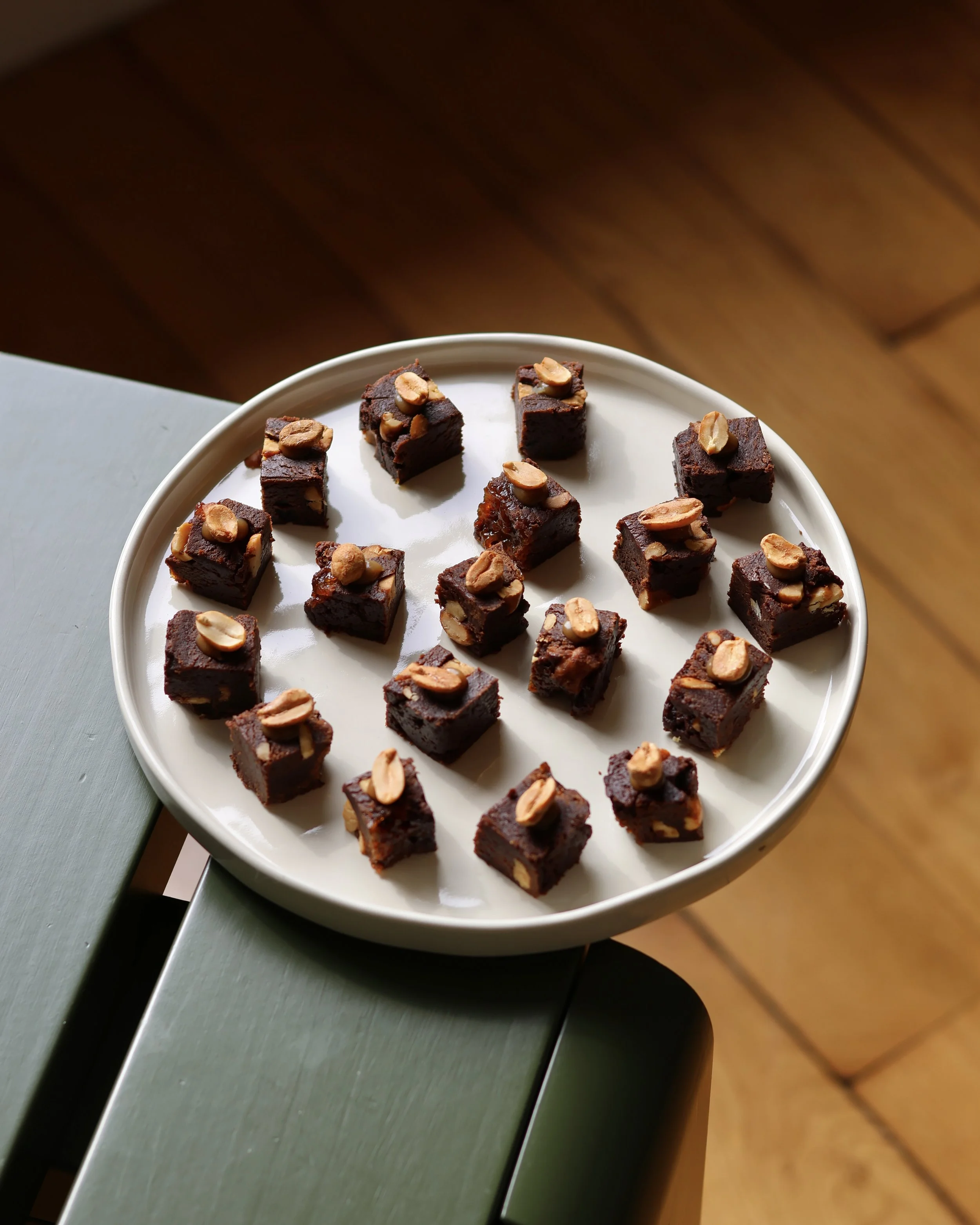 Carré de brownies au chocolat avec des amandes effilées sur une assiette blanche.