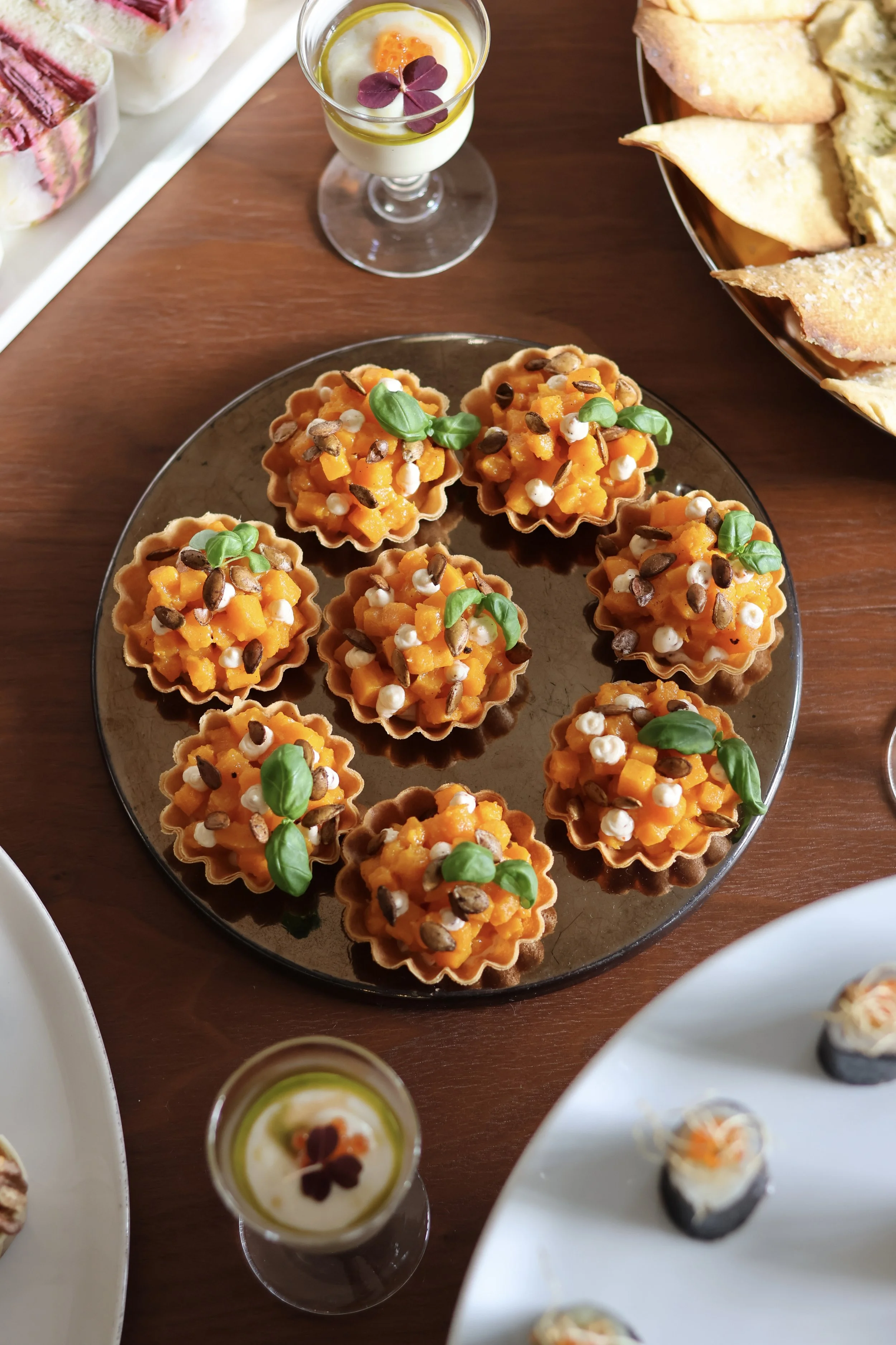 Mini tartelettes garnies de purée de citrouille, décorées de petites feuilles vertes, de graines et de petites billes blanches. 