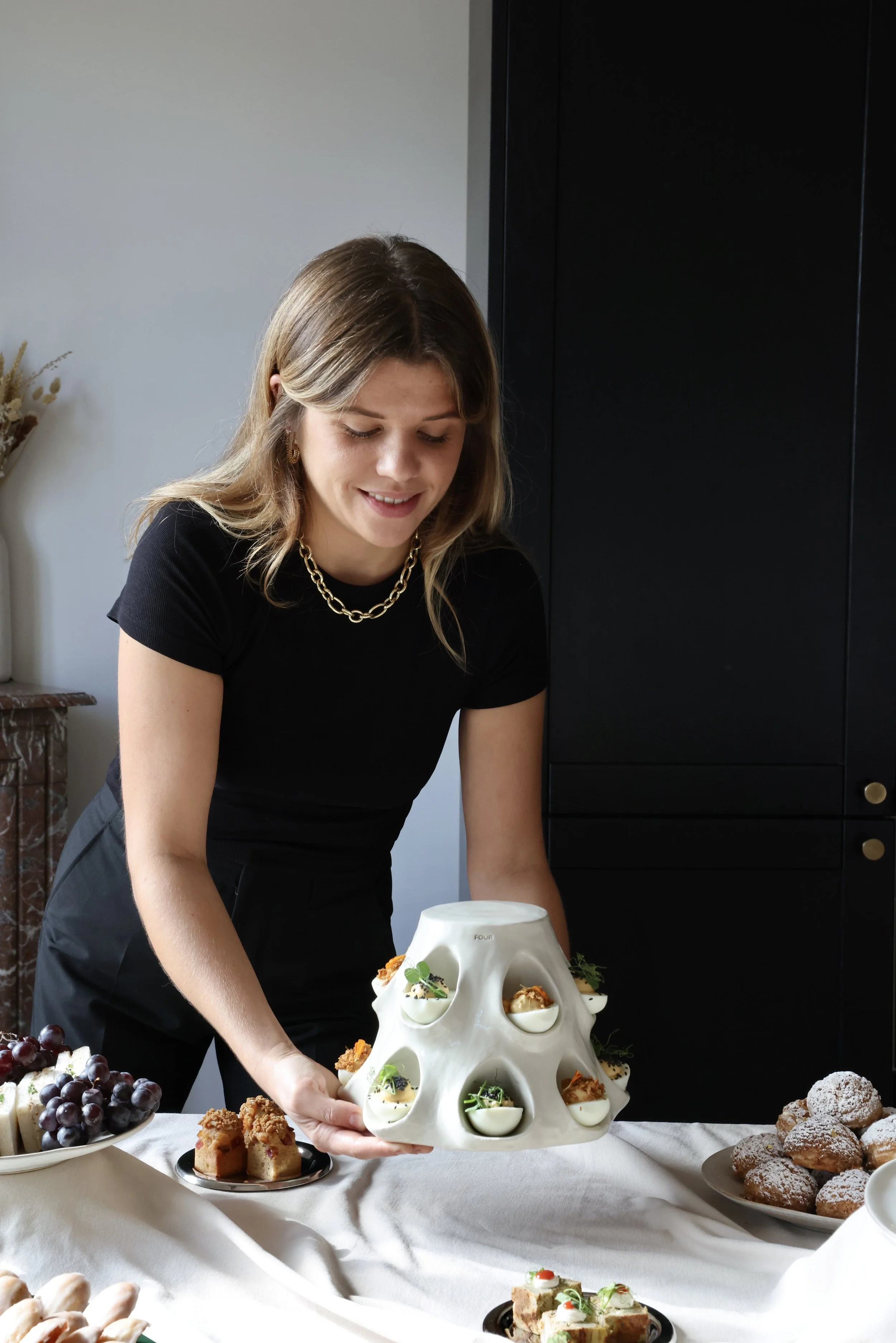 Une femme souriante présente une pièce montée sophistiquée pour un événement ou un buffet.