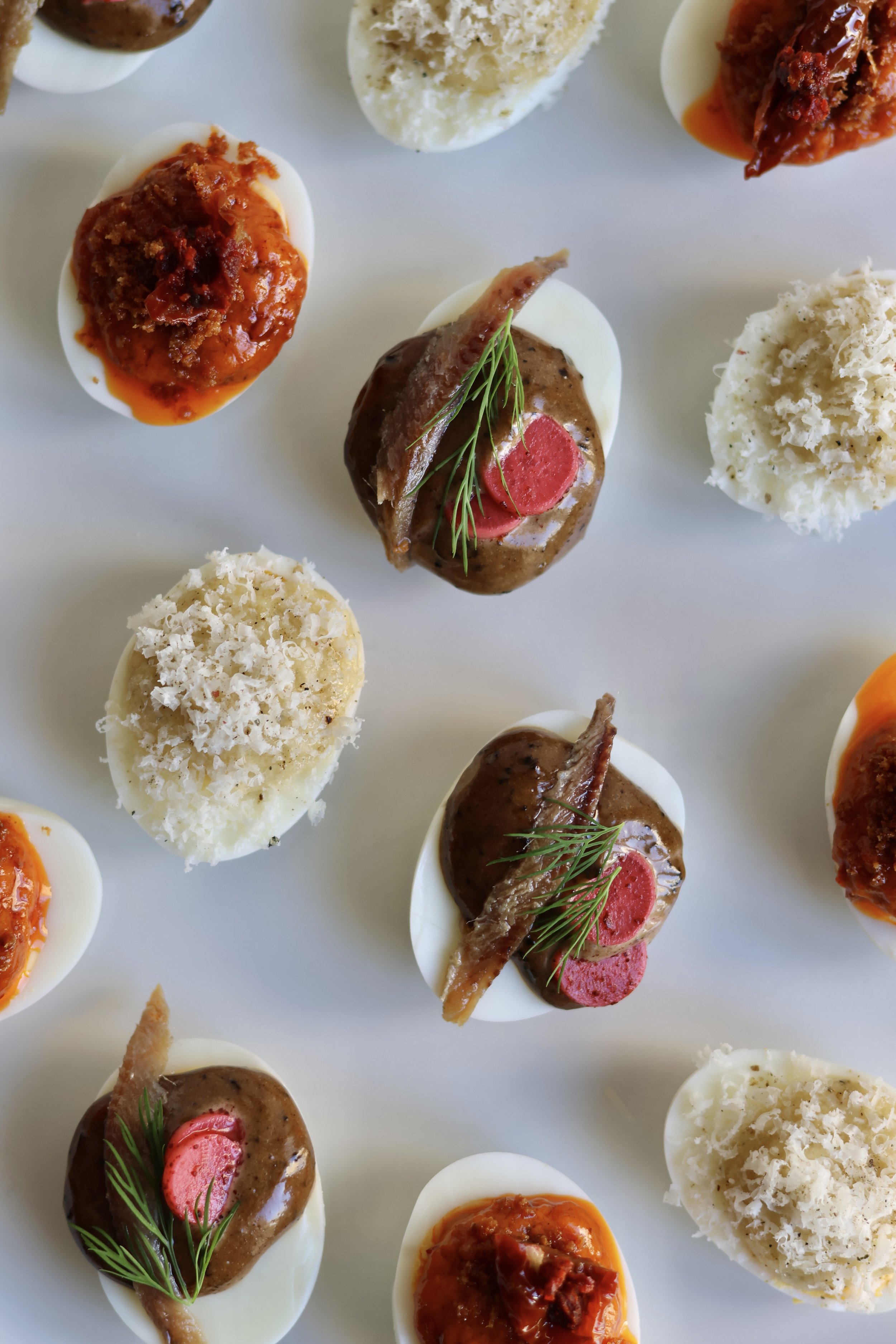 Petits œufs remplis de différentes garnitures, garnis de herbes et de morceaux de viande.