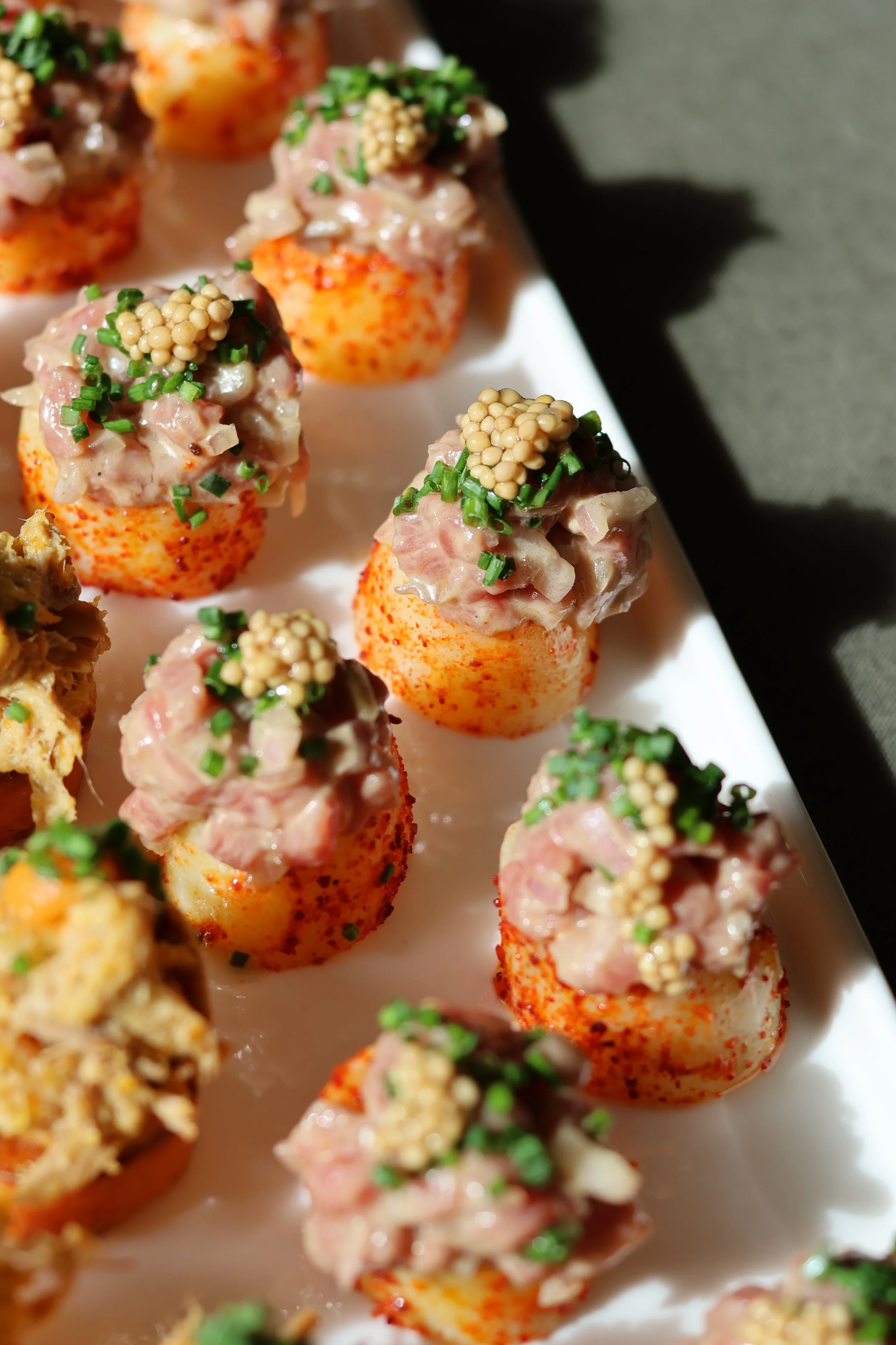Garnitures de pommes de terre farcies avec mayonnaise, ciboulette et graines de moutarde, servies sur une assiette blanche.