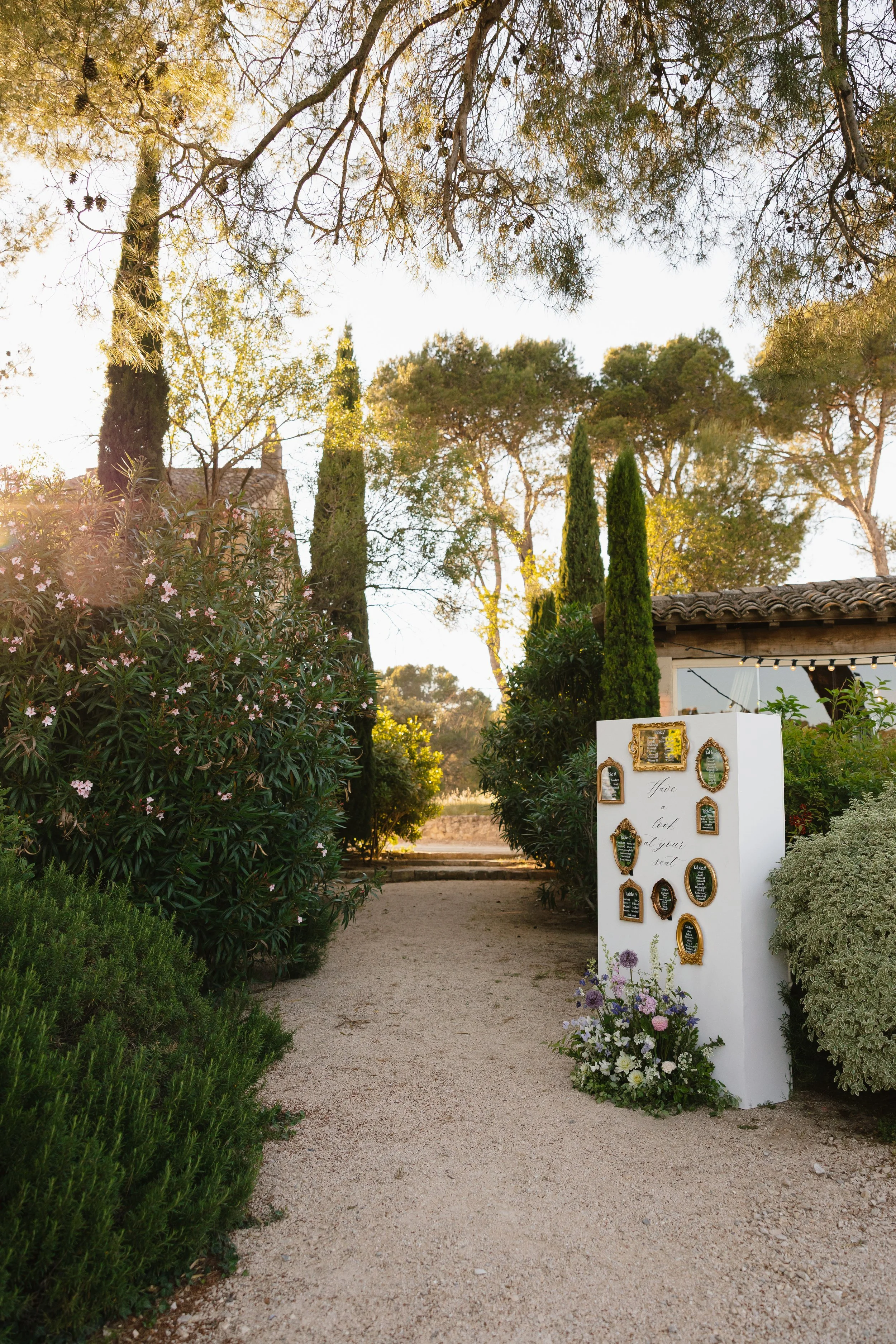Décor de mariage en plein air avec un panneau d'accueil et des fleurs, entouré d'arbres et de végétation.