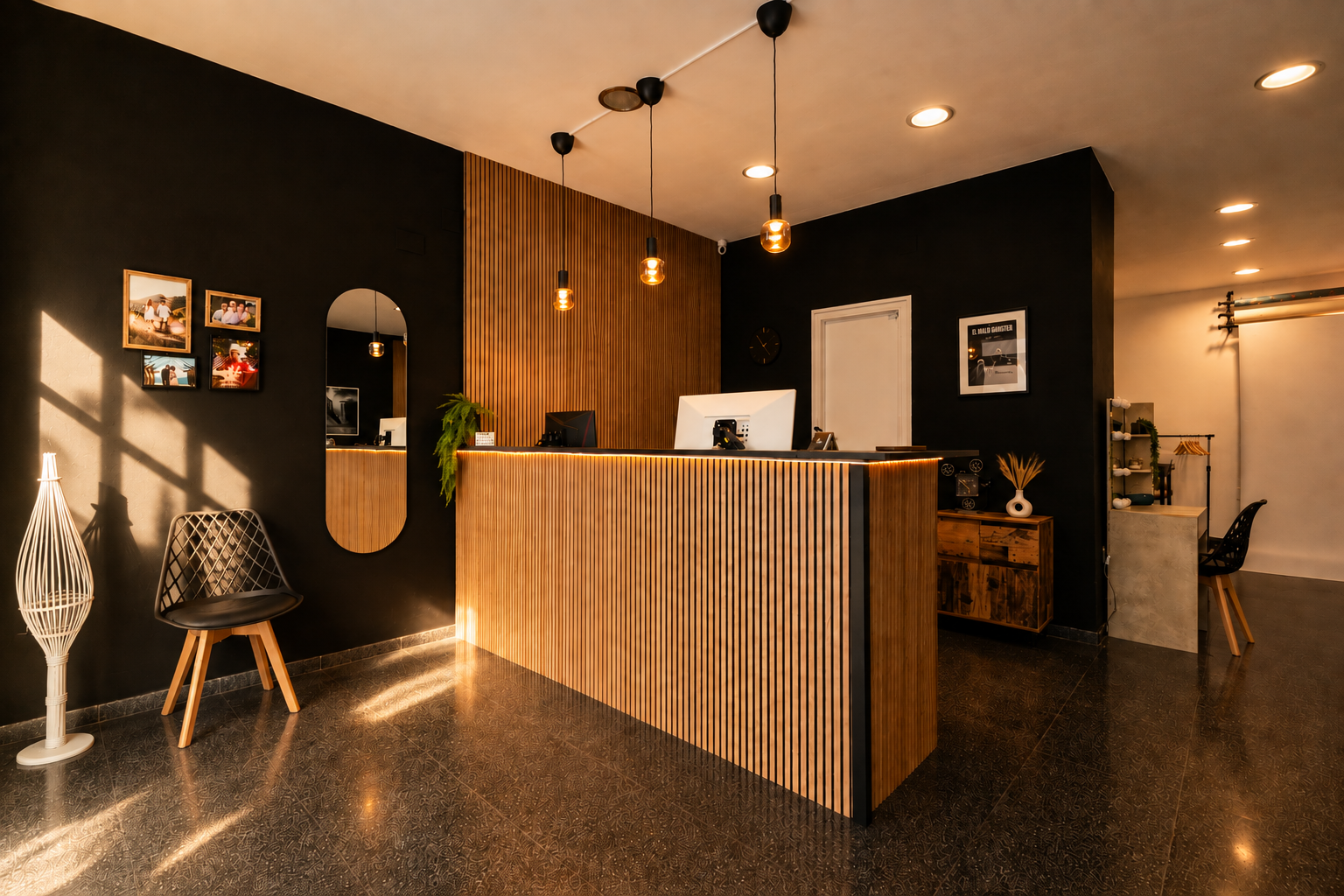 Recepción del estudio con muro negro, madera clara y detalles de iluminación cálida, incluyendo una silla y plantas decorativas.