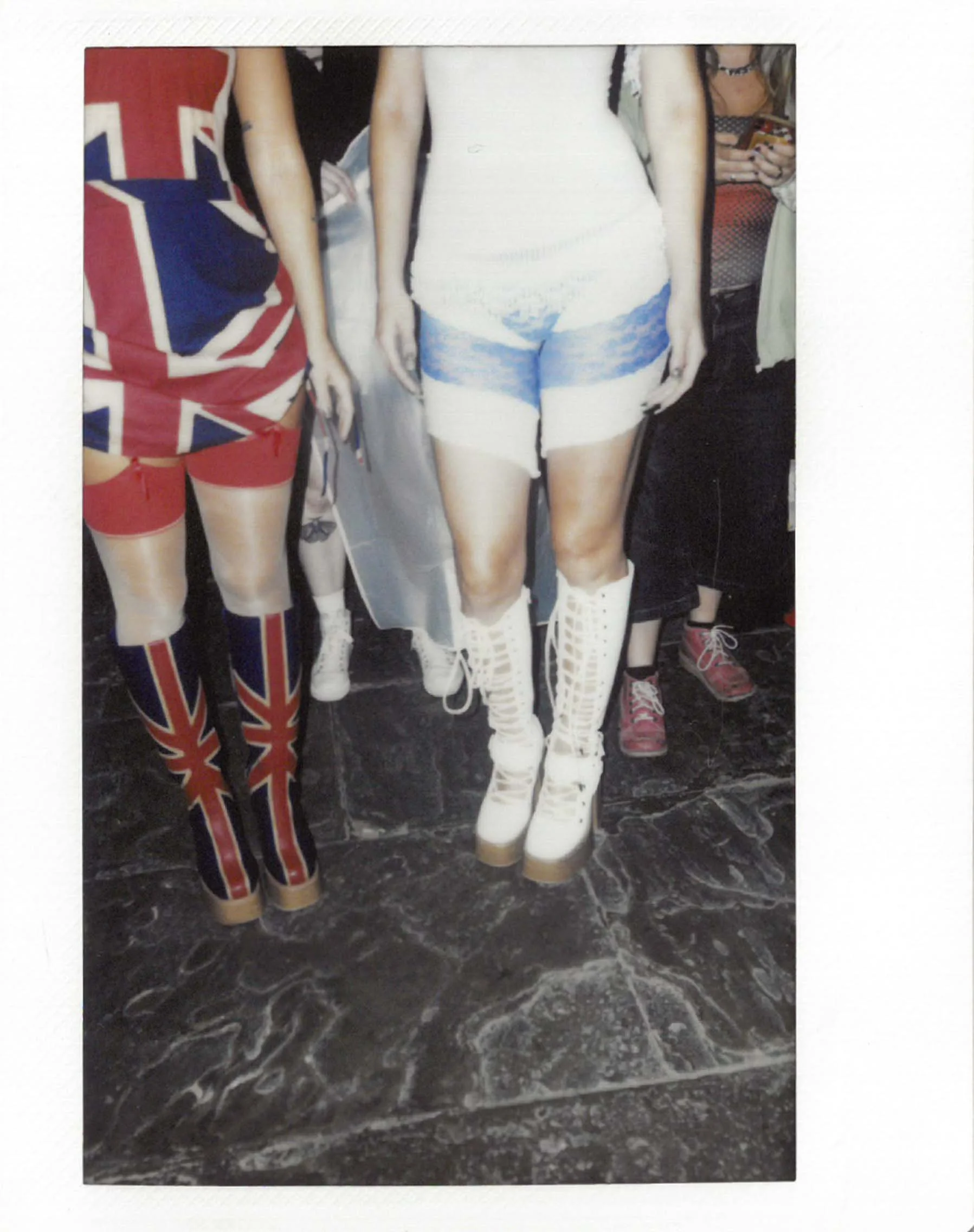 Close-up of two women standing together, showcasing fashion outfits and footwear from Sinead O'Gorey, with emphasis on their legs and shoes.