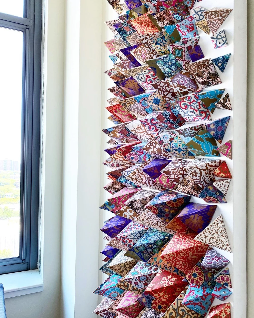 DIY wall decor ideas with colourful patterned paper triangles arranged as a mosaic on a white wall