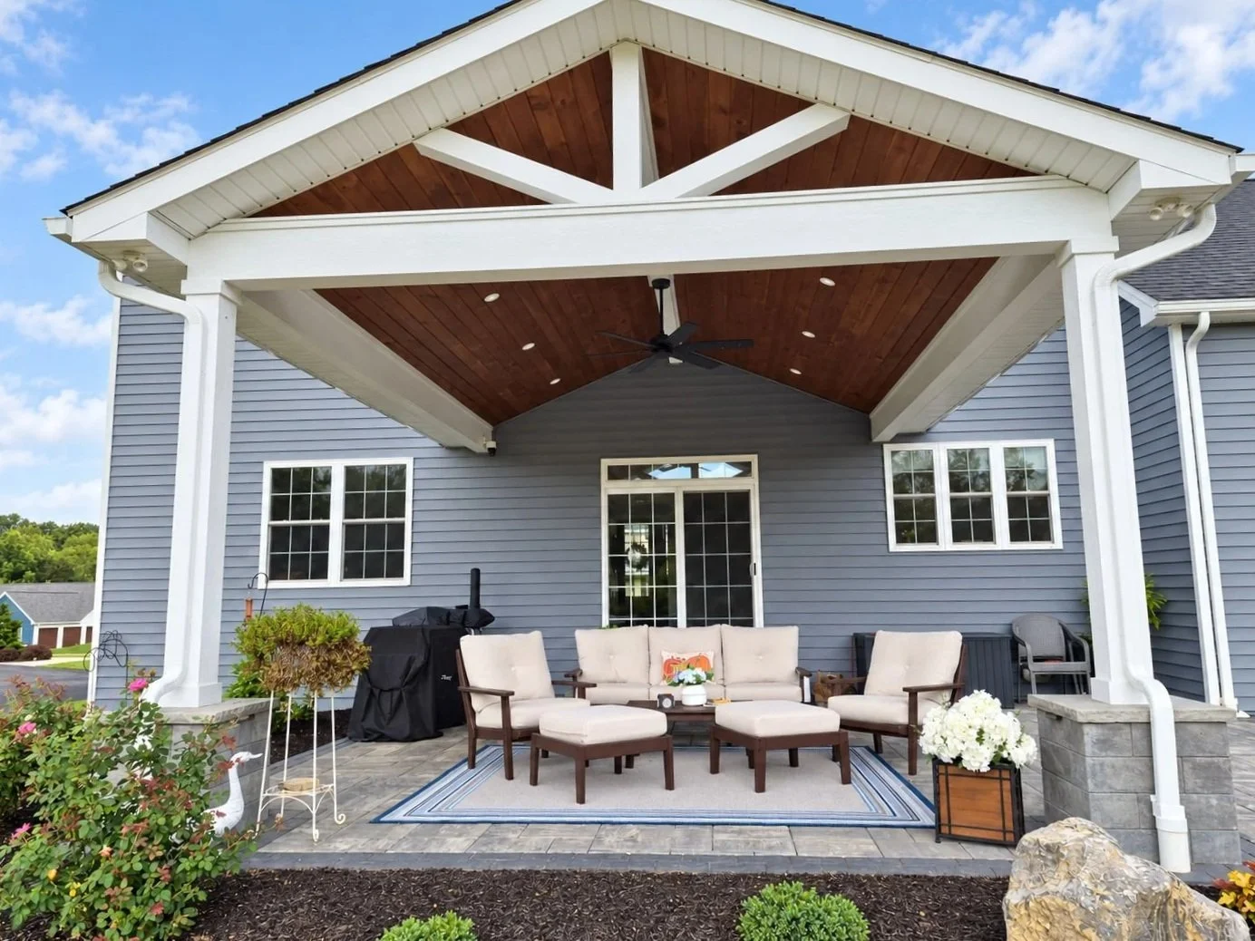 Covered pavilion opening onto stone patio and backyard