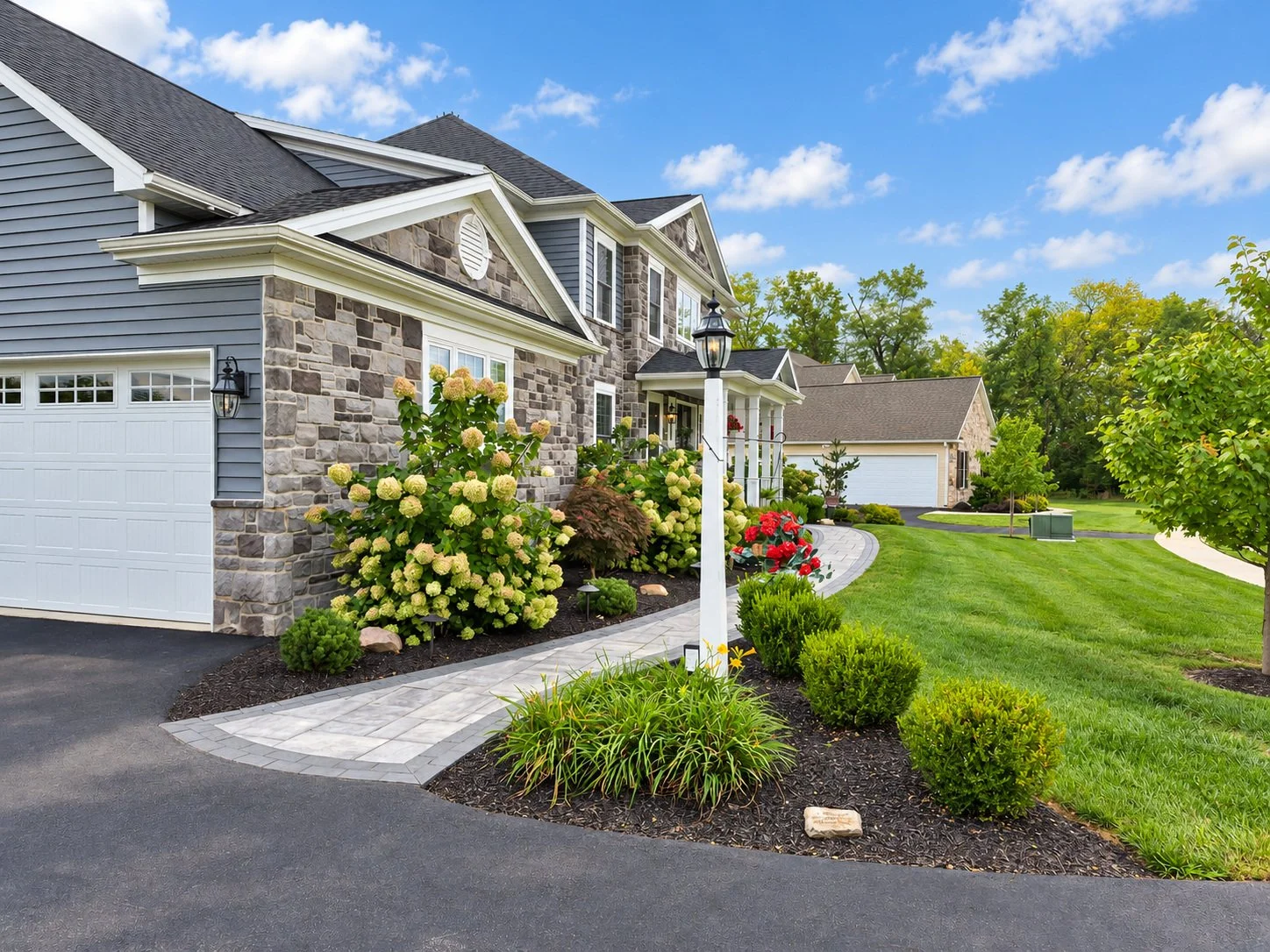 Landscaped driveway and garage approach with manicured lawn