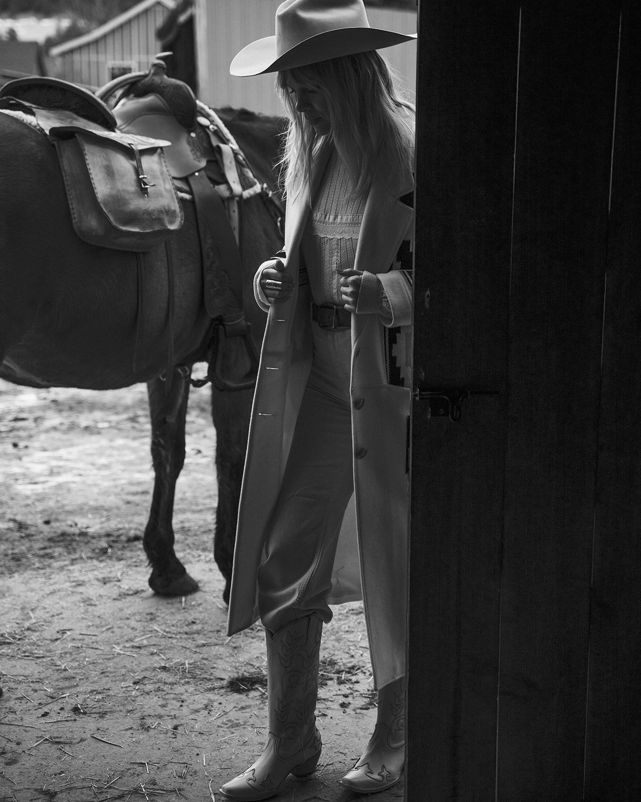 Black and white image of person in cowboy attire with horse