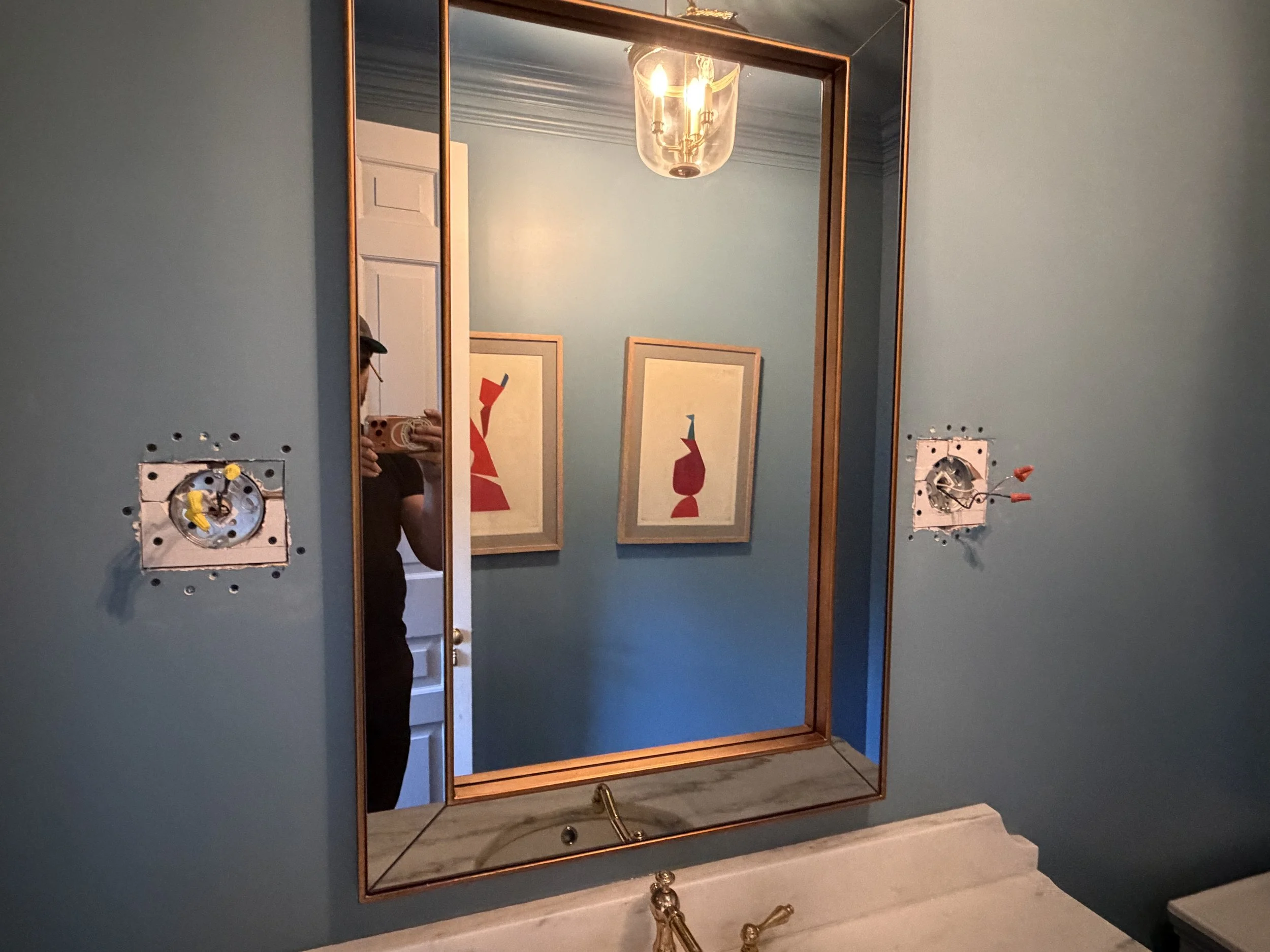 a photo of a newly installed antique mirror in a color drenched powder room | Norcross Builders