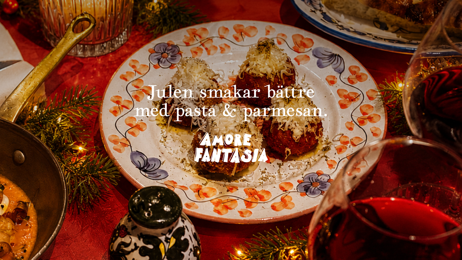 Ett julbord med pastarätter täckta med ost, på en julduk med juldekorationer och glas vin