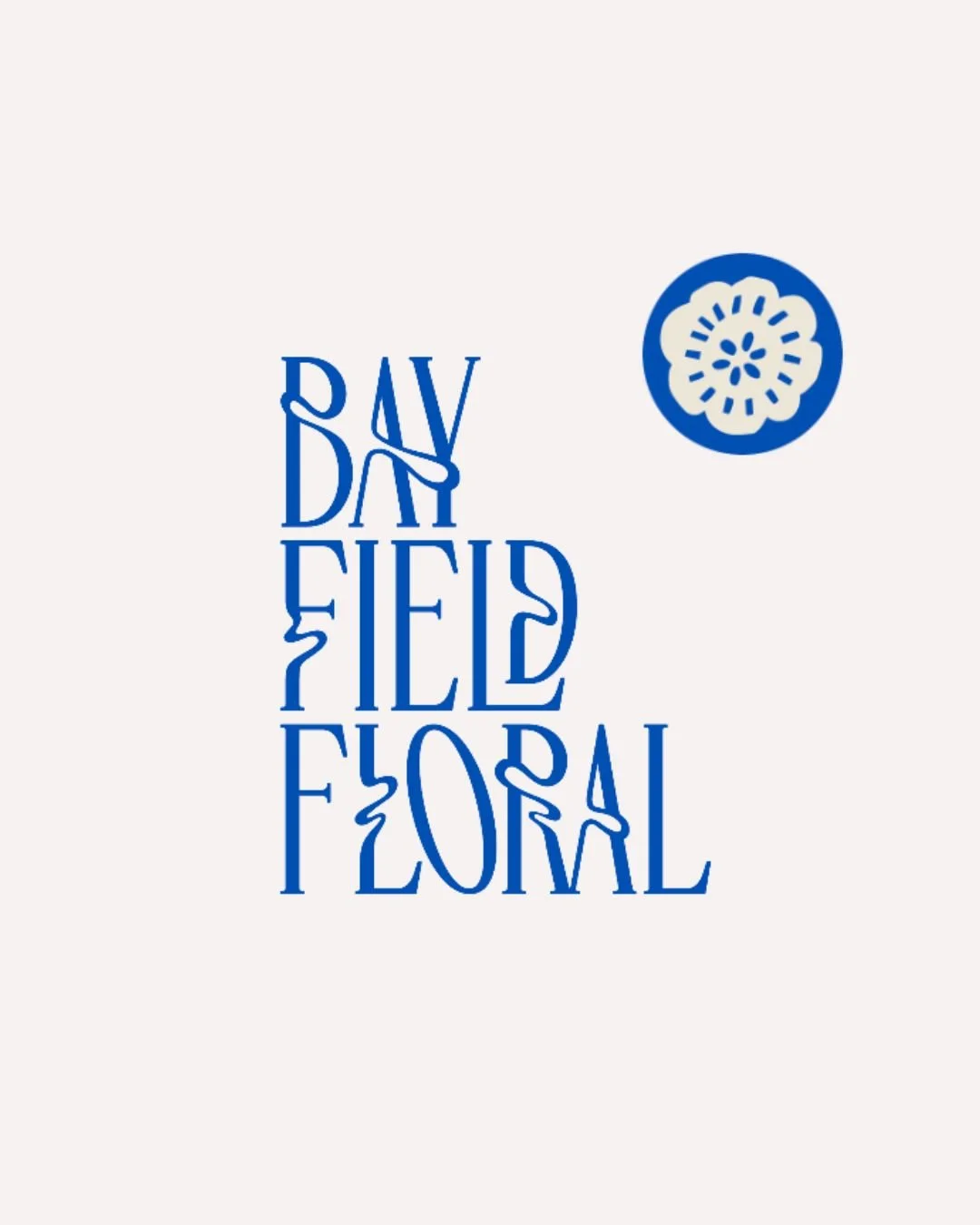 Blue text on a white background reads 'DAYDREAMING' with the letters arranged vertically and stylized. A blue circular floral design is located to the right of the text.