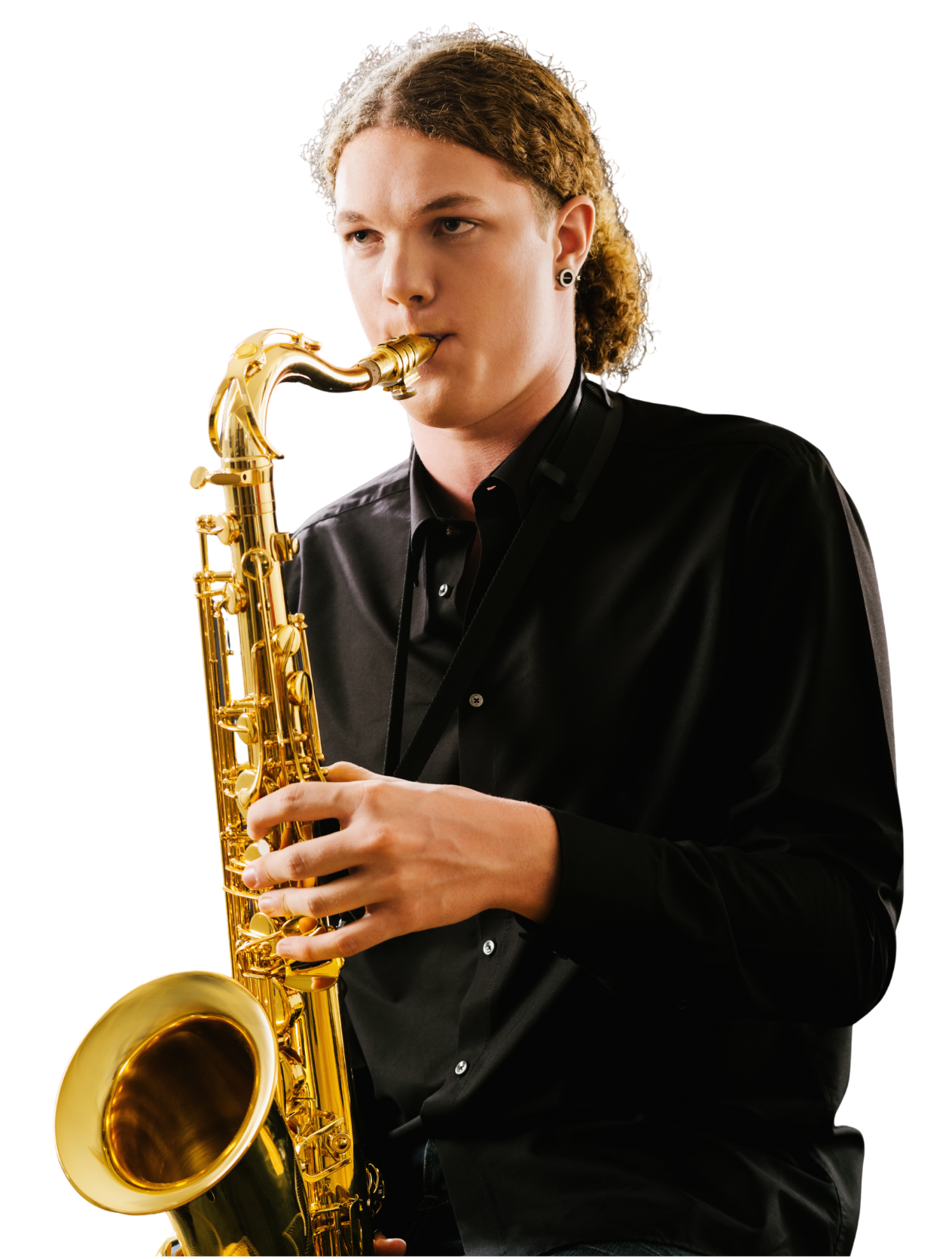 Young man with long curly hair playing a gold-colored saxophone, wearing a black button-up shirt, against a plain background.