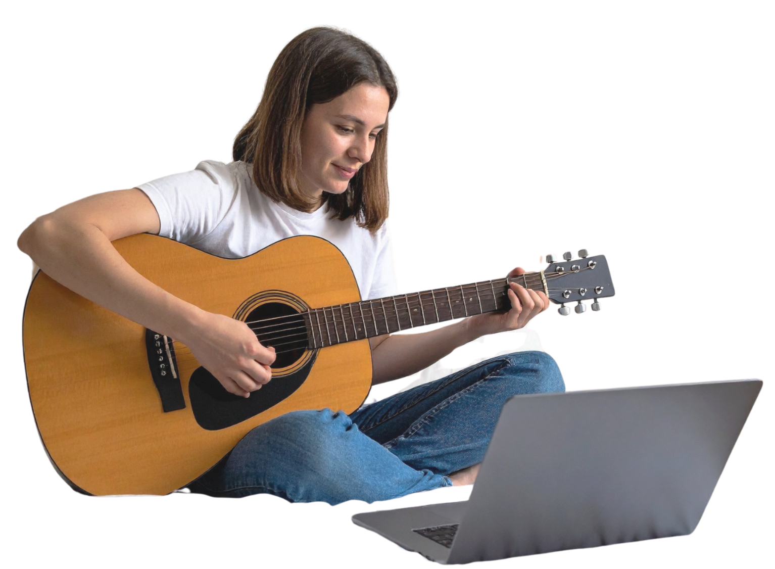 A young woman sitting cross-legged with a laptop and playing an acoustic guitar