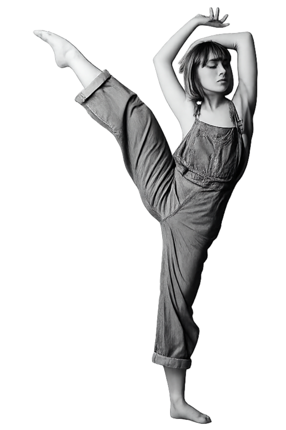 A woman in casual clothing performing a high kick with one leg raised and arms overhead, with a focused expression.