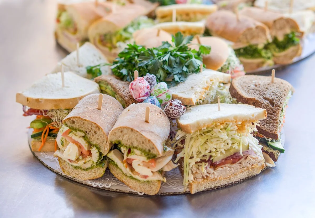 South Coast Deli catering platter with assorted half sandwiches on Italian rolls and wheat bread, garnished with fresh herbs, Santa Barbara