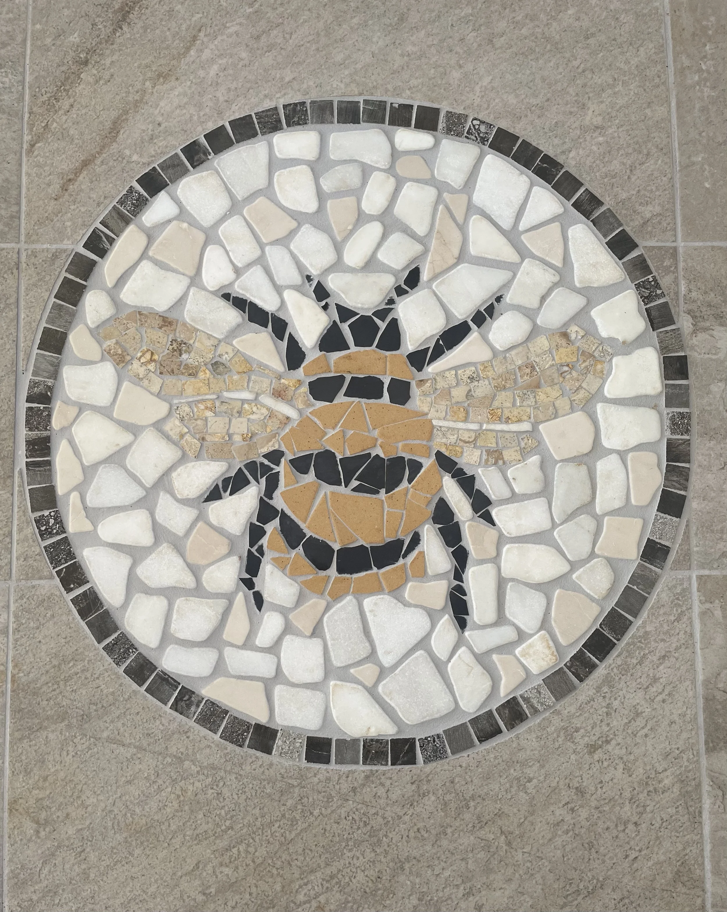 Decorative circular mosaic tile design on a beige tiled floor
