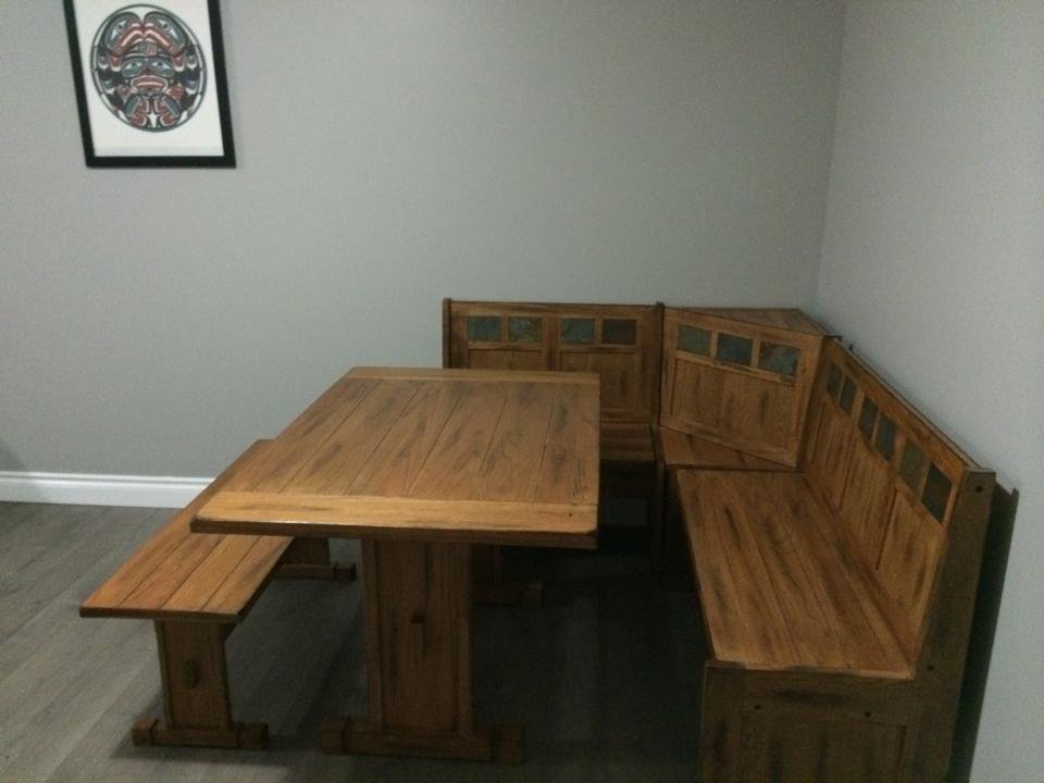A wooden dining nook with a table and bench seating in a corner of a room, with a framed artwork of a black and white orca whale on the wall.