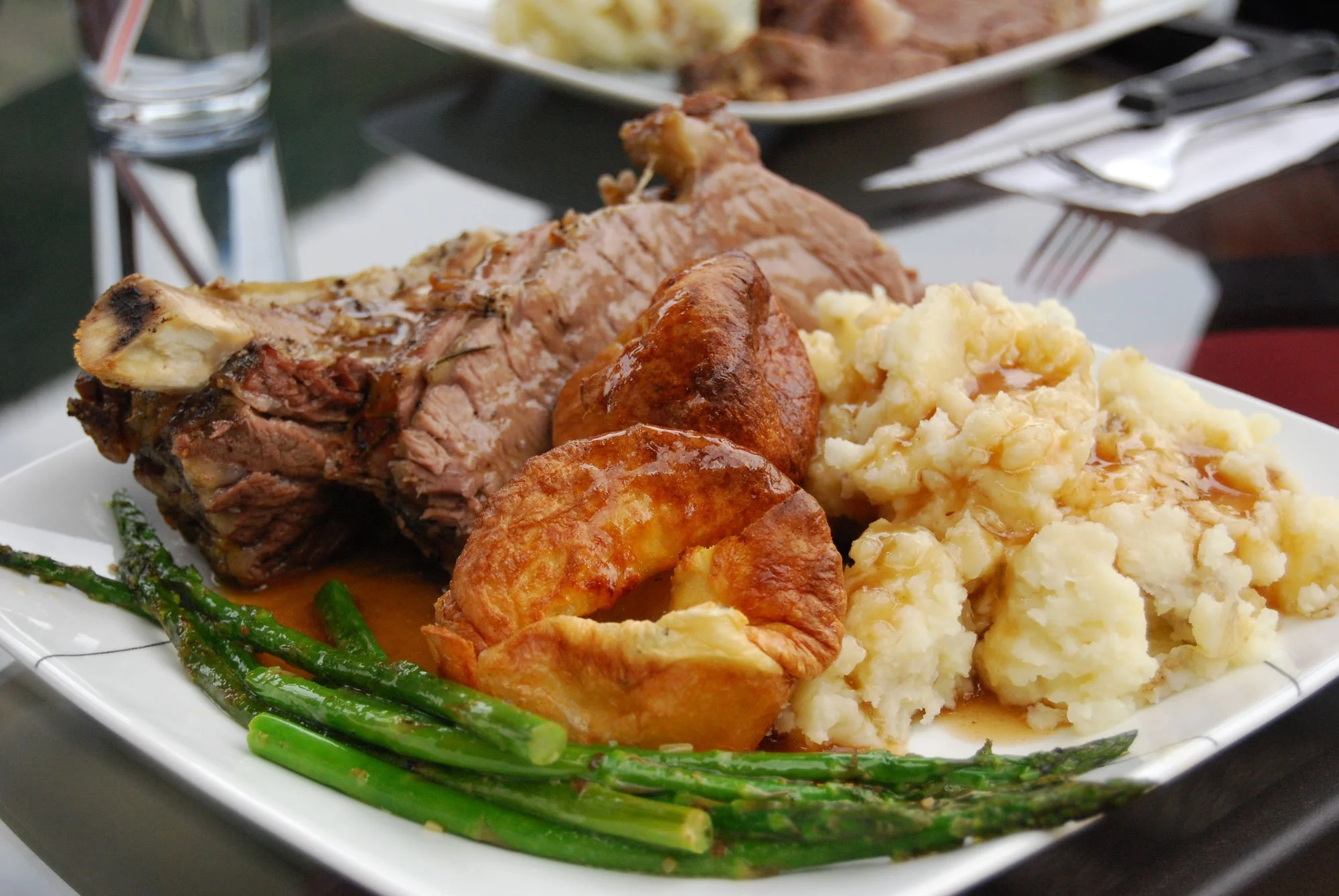A plate of food featuring mashed potatoes with gravy, a baked chicken drumstick, green beans, a portion of roast beef, and a slice of roasted potato.
