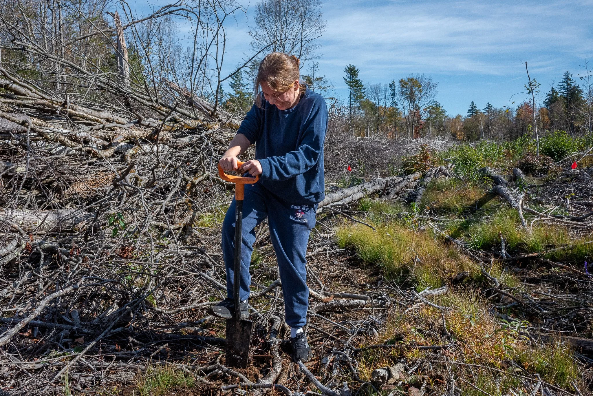 A student volunteer from a local college uses a bladed shovel to break ground near the slashwall.