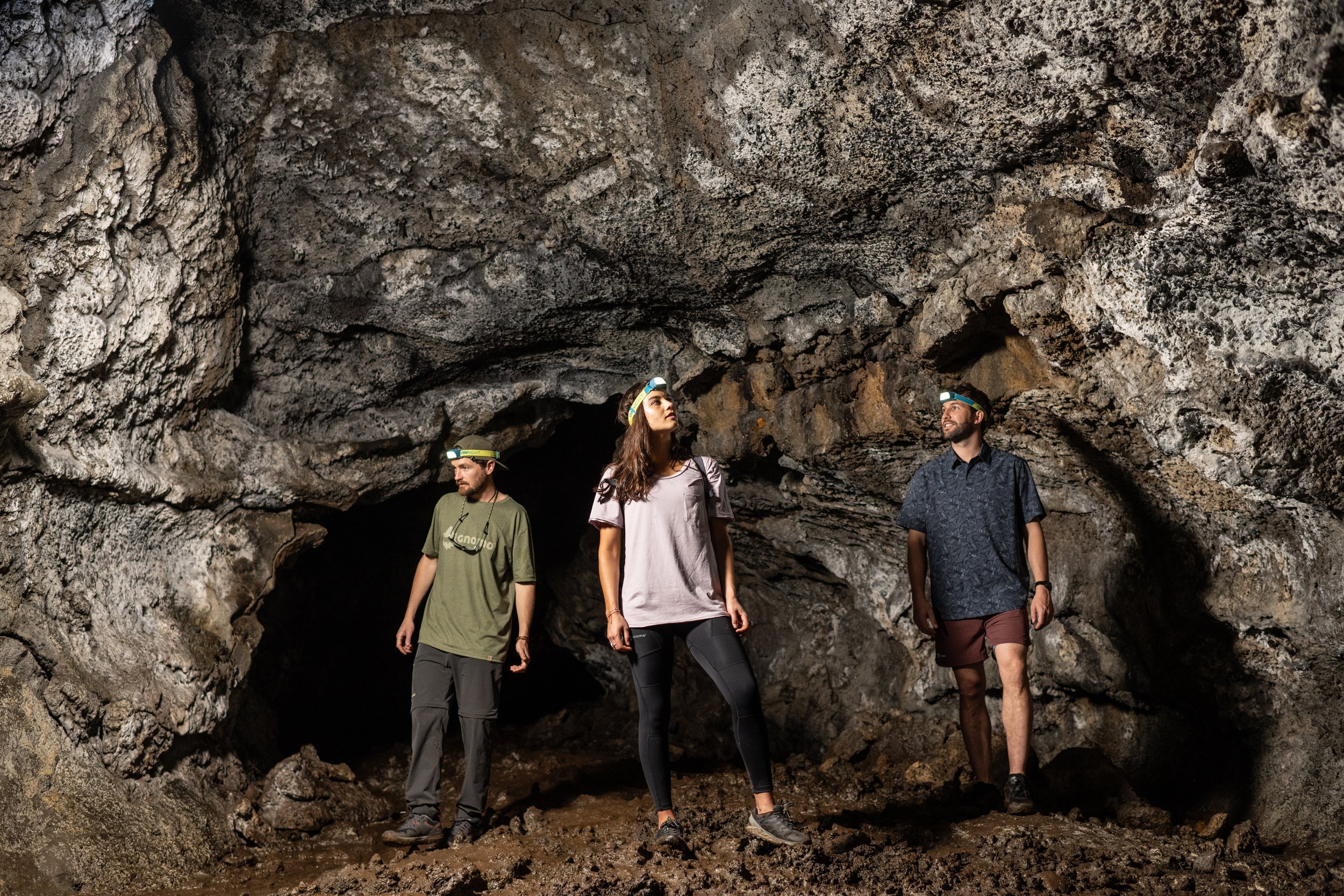 Tres personas con linternas explorando el interior de una cueva.