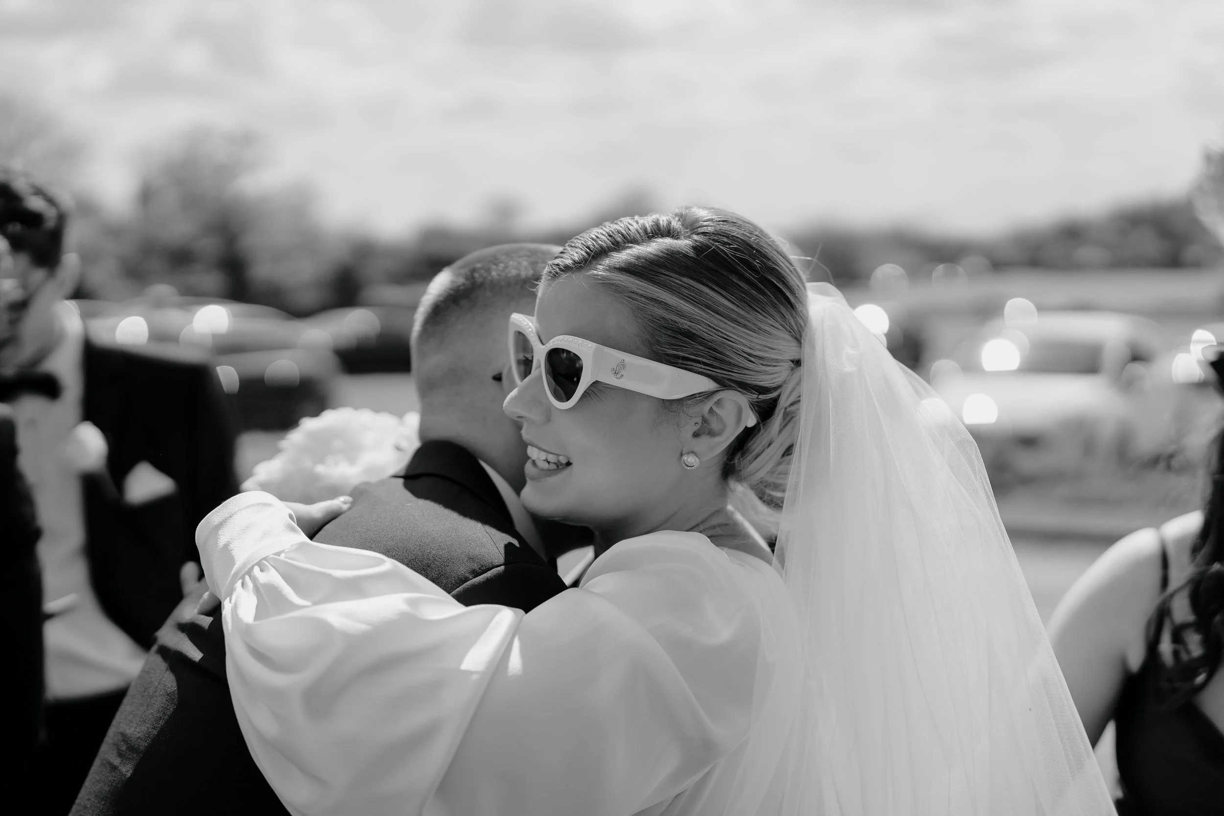 Stylish bride hugging groom wearing sunglasses