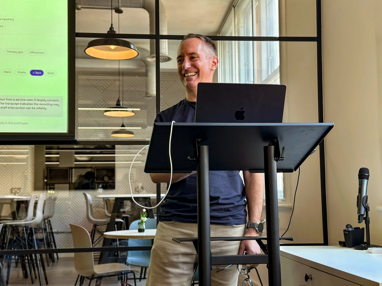 A team member laughing while presenting at a lectern