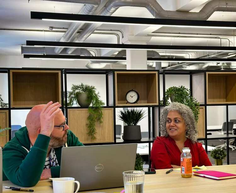 Two colleagues in conversation at a shared desk