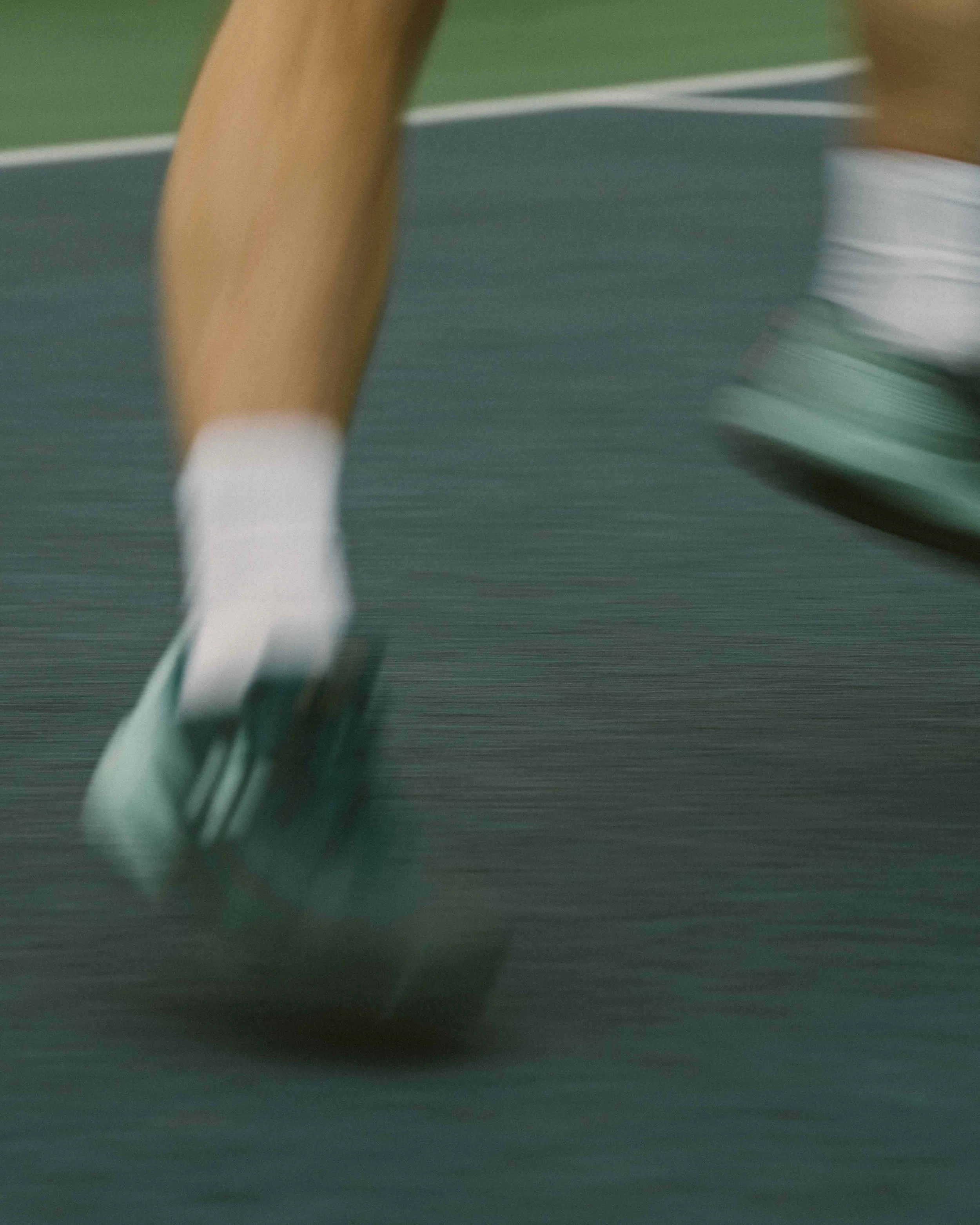 Blurred motion of a person's legs and feet skating on an indoor rink.
