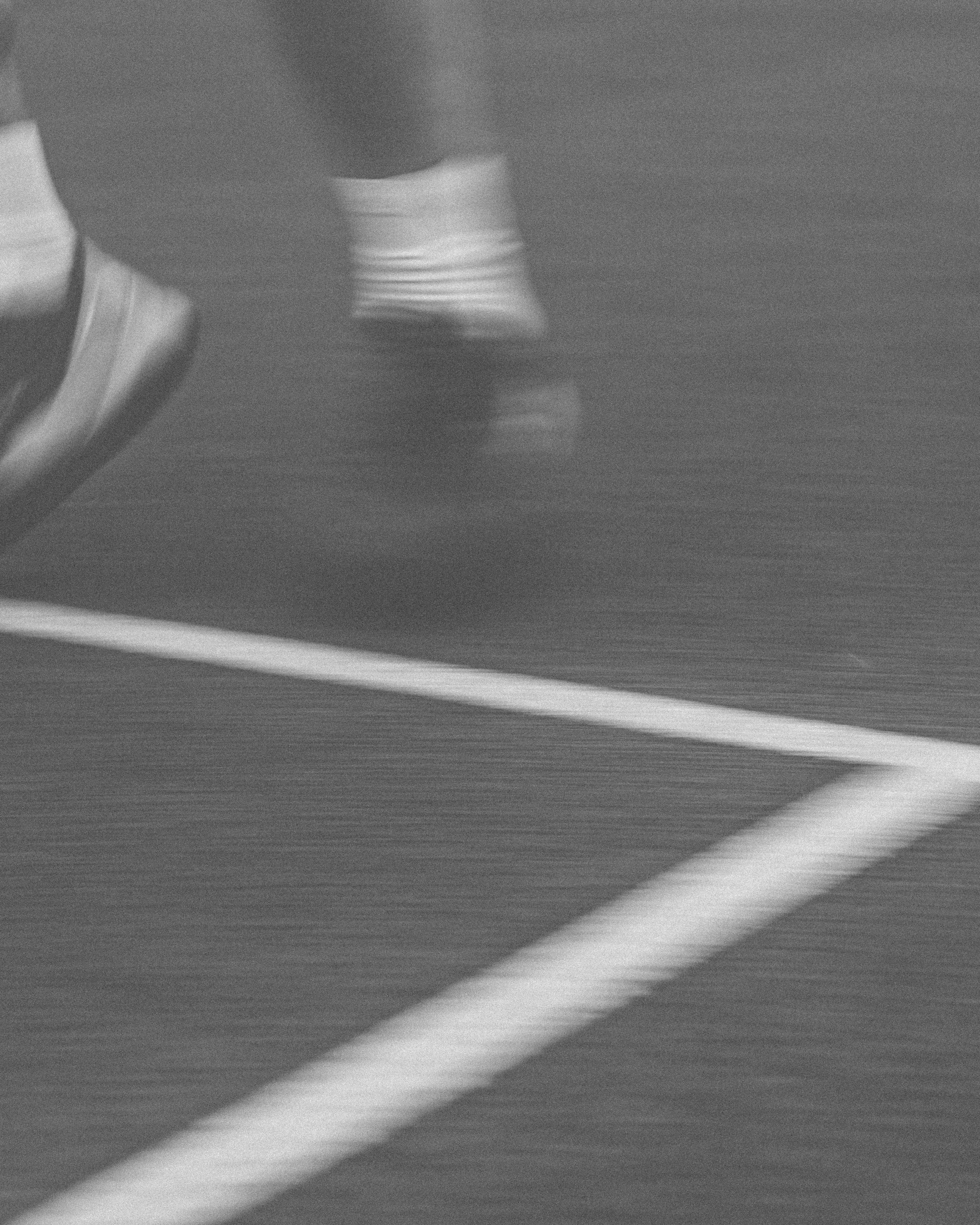 Close-up of a person running on a treadmill, focusing on their legs and sneakers.