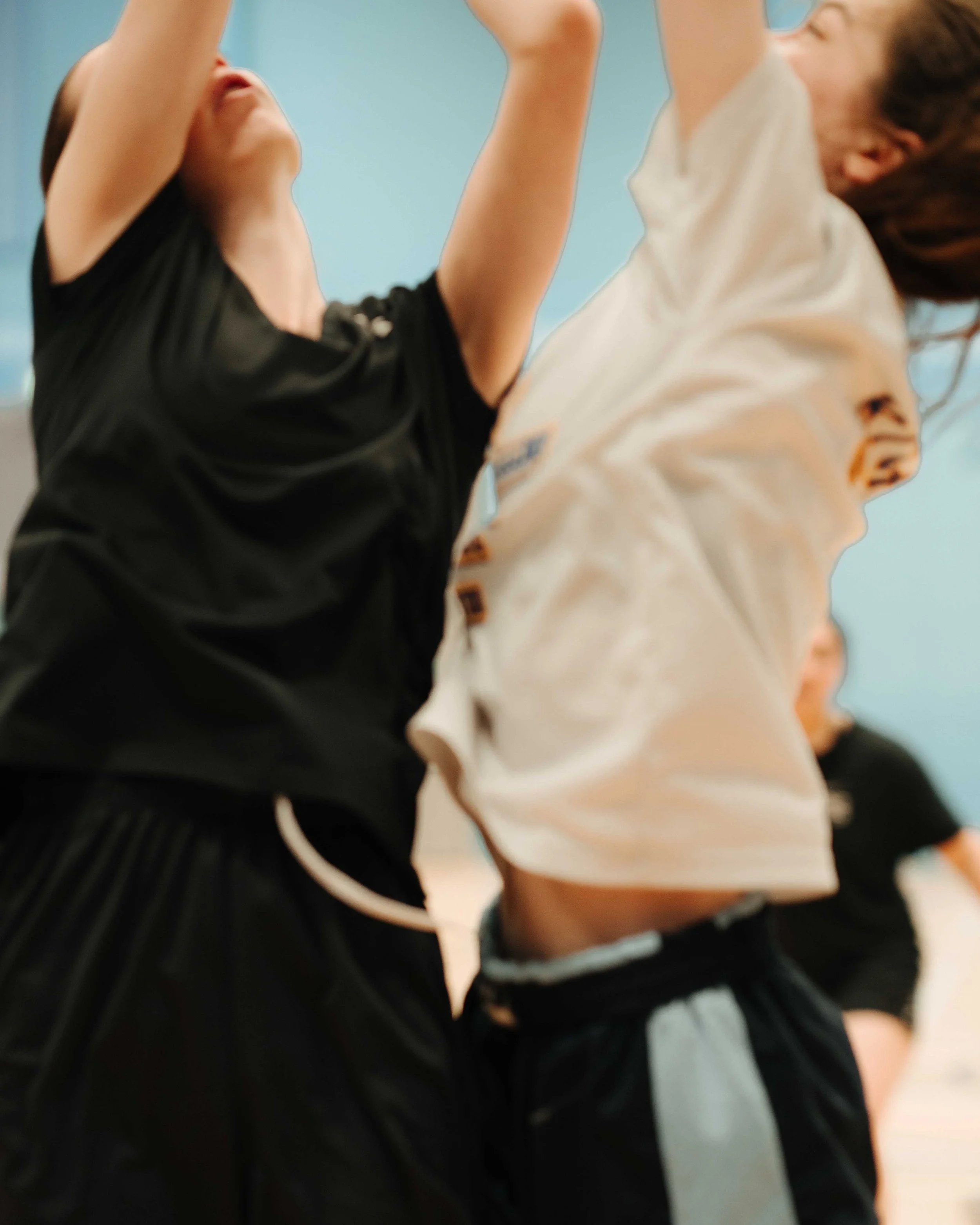 Close-up of young people jumping or dancing indoors, wearing casual athletic clothes.